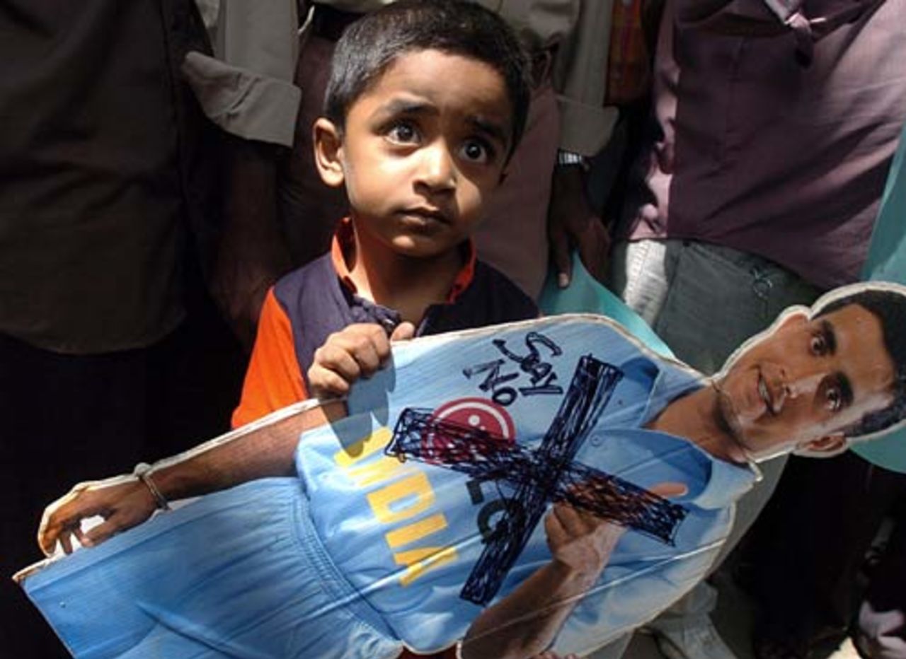 A young Indian boy holds a cutout of Sourav Ganguly as cricket fans shout slogans against Ganguly, Bangalore, September 26, 2005