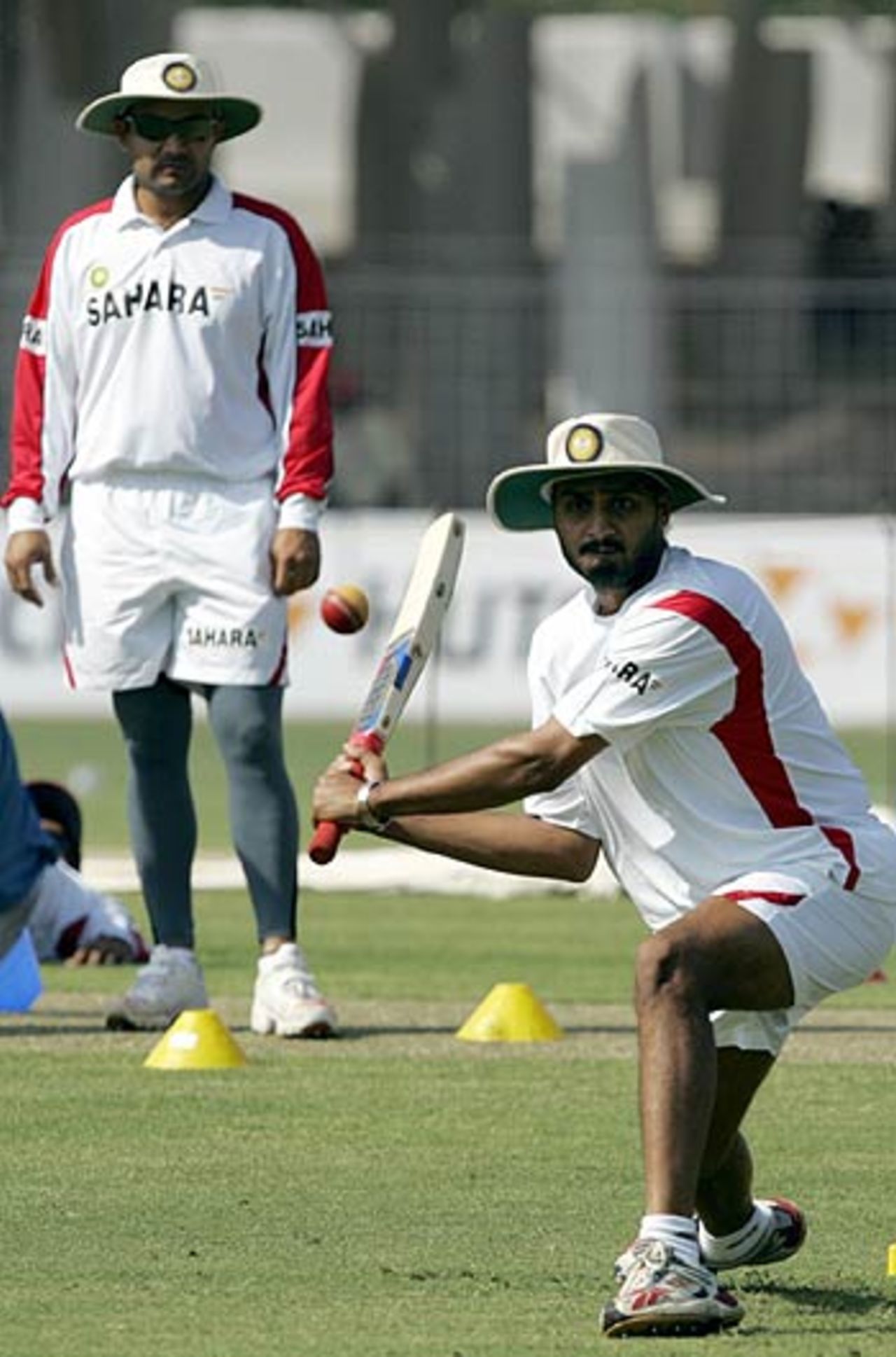 Virender Sehwag watches teammate Harbhajan Singh play a shot during a practice session, Madhavrao Scindia Cricket Ground, Rajkot, November 8, 2005
