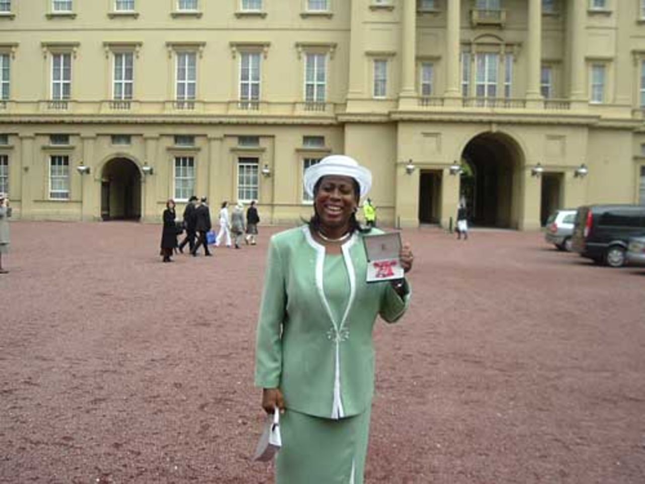 Nadine George stands outside Buckingham palace to receive her MBE