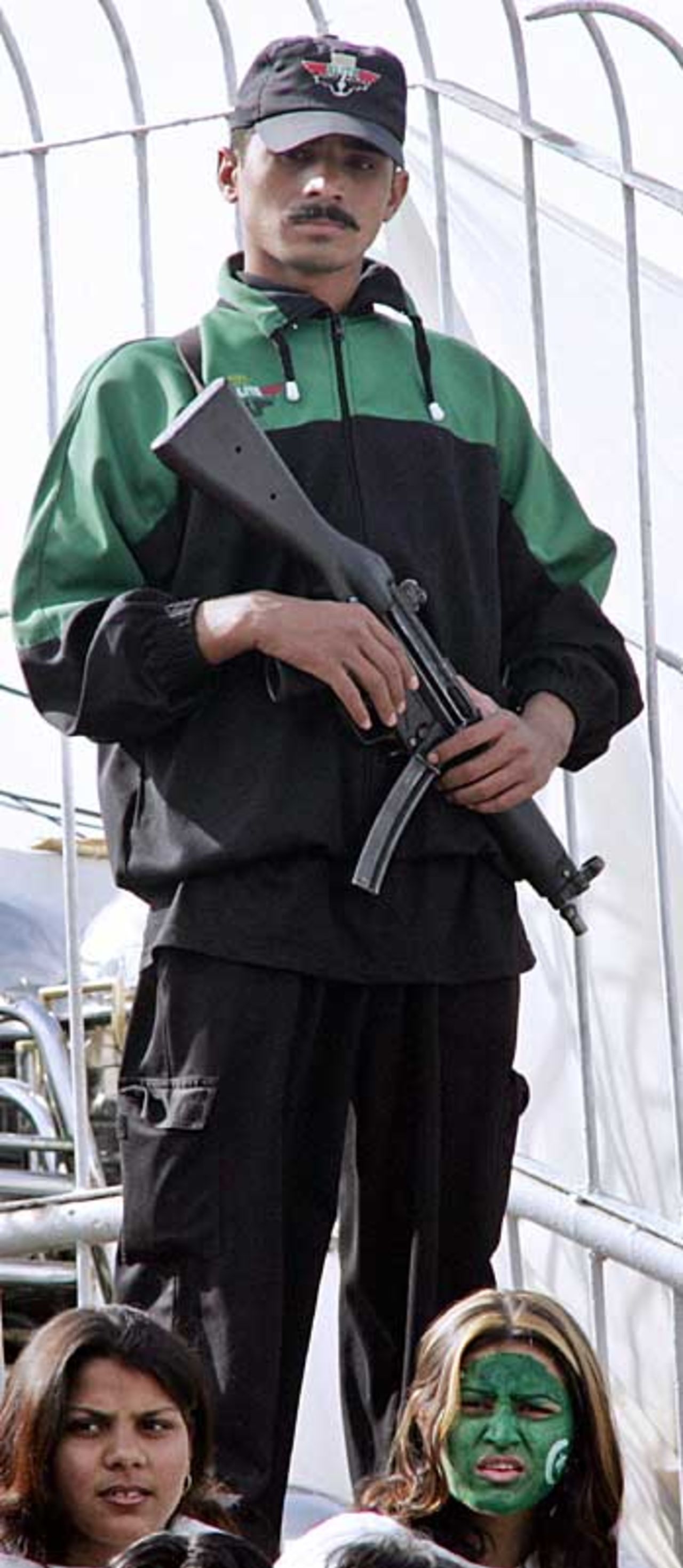 A Pakistani policeman stands guard in front of two Pakistani supporters, Pakistan v India, 2nd Test, 4th day, Faisalabad, January 24 2006
