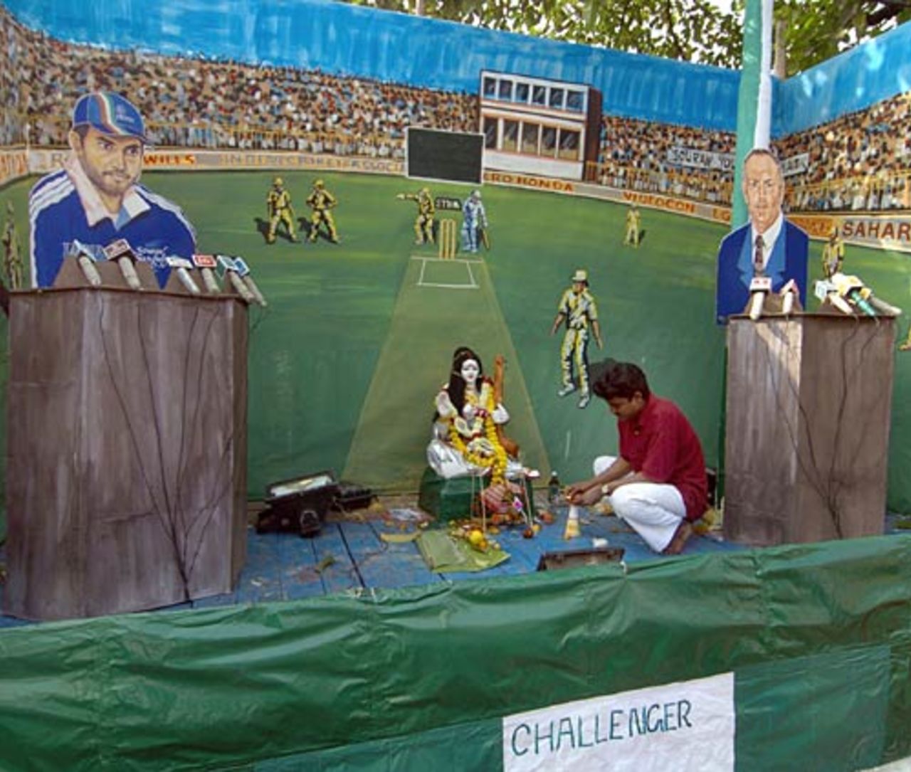 A worker lights-up a candle, a ritual of worshipping Sarasawati, (idol in the middle) Hindu goddess of knowledge, music and creative arts, while the worship place has been decorated by cut-outs of Sourav Ganguly and Greg Chappell, depicted as challenger, Kolkata, India, February 4 2005