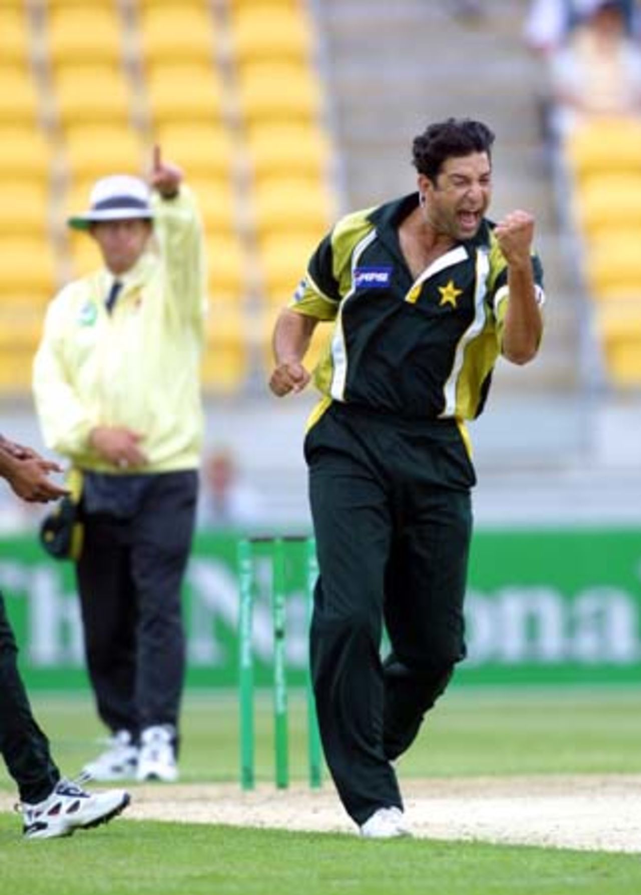 Pakistan opening bowler Wasim Akram punches the air in celebration of dismissing New Zealand opening batsman Stephen Fleming for one, adjudged out leg before wicket by umpire Dave Quested (raising his finger in the background). 3rd One-Day International: New Zealand v Pakistan at WestpacTrust Stadium, Wellington, 22 February 2001.