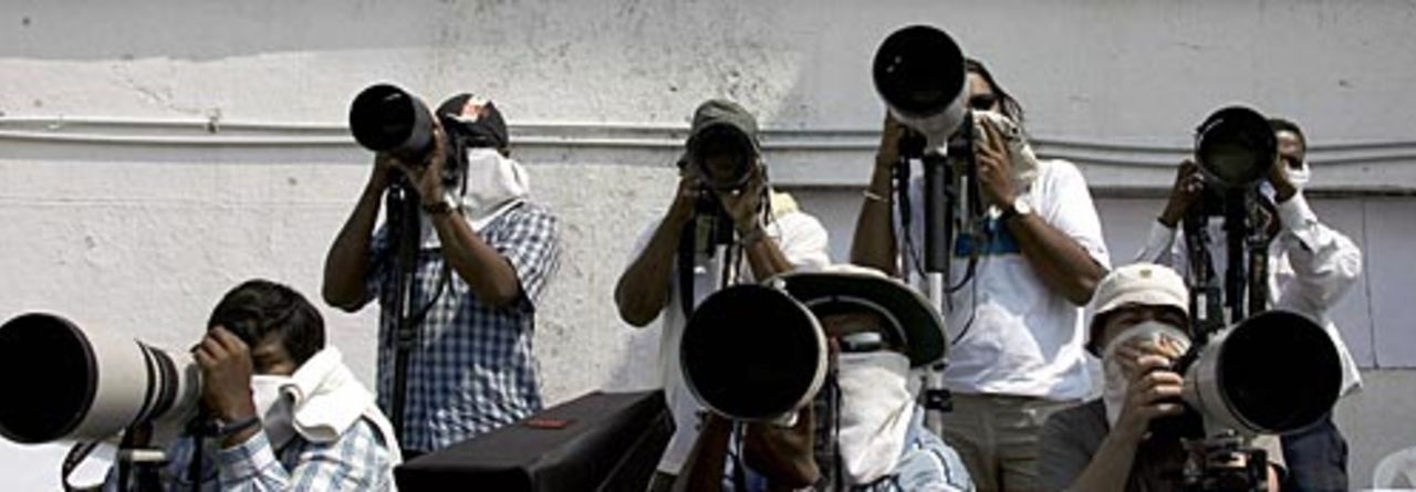 Photographers cover their mouths and noses to protect against the smell of an open sewer near their position , India v England, 1st Test, Nagpur, March 5, 2006
