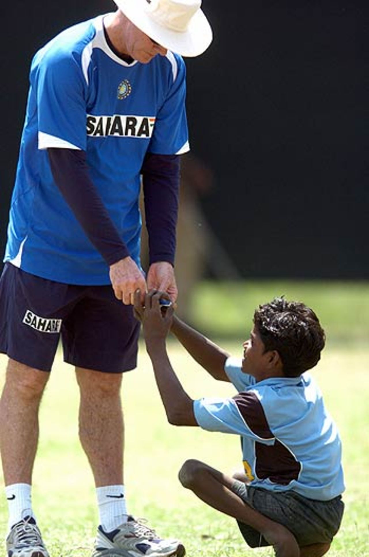 Greg Chappell signs an autograph for a physically disabled child during practice at the Nahar Singh Cricket Stadium, Faridabad, March 30, 2006