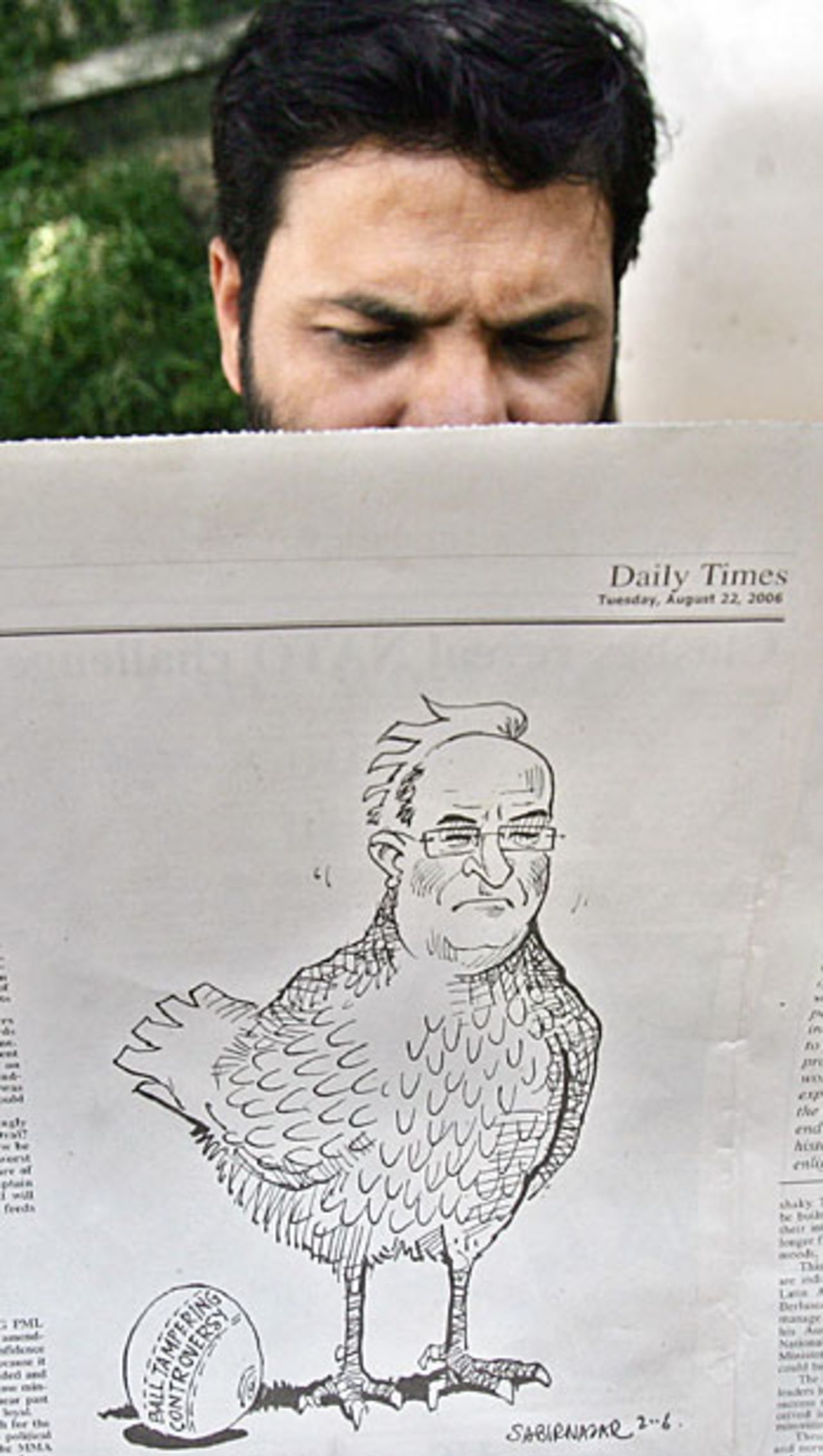 A Pakistani reader holds a newspaper featuring a cartoon showing Darrell Hair as a chicken, Islamabad, August 22, 2006