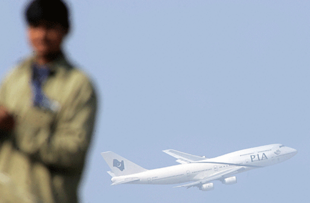 A PIA flight takes off in the backdrop of a groundsman's work at the Rawalpindi Cricket Stadium, Rawalpindi, February 9, 2006
