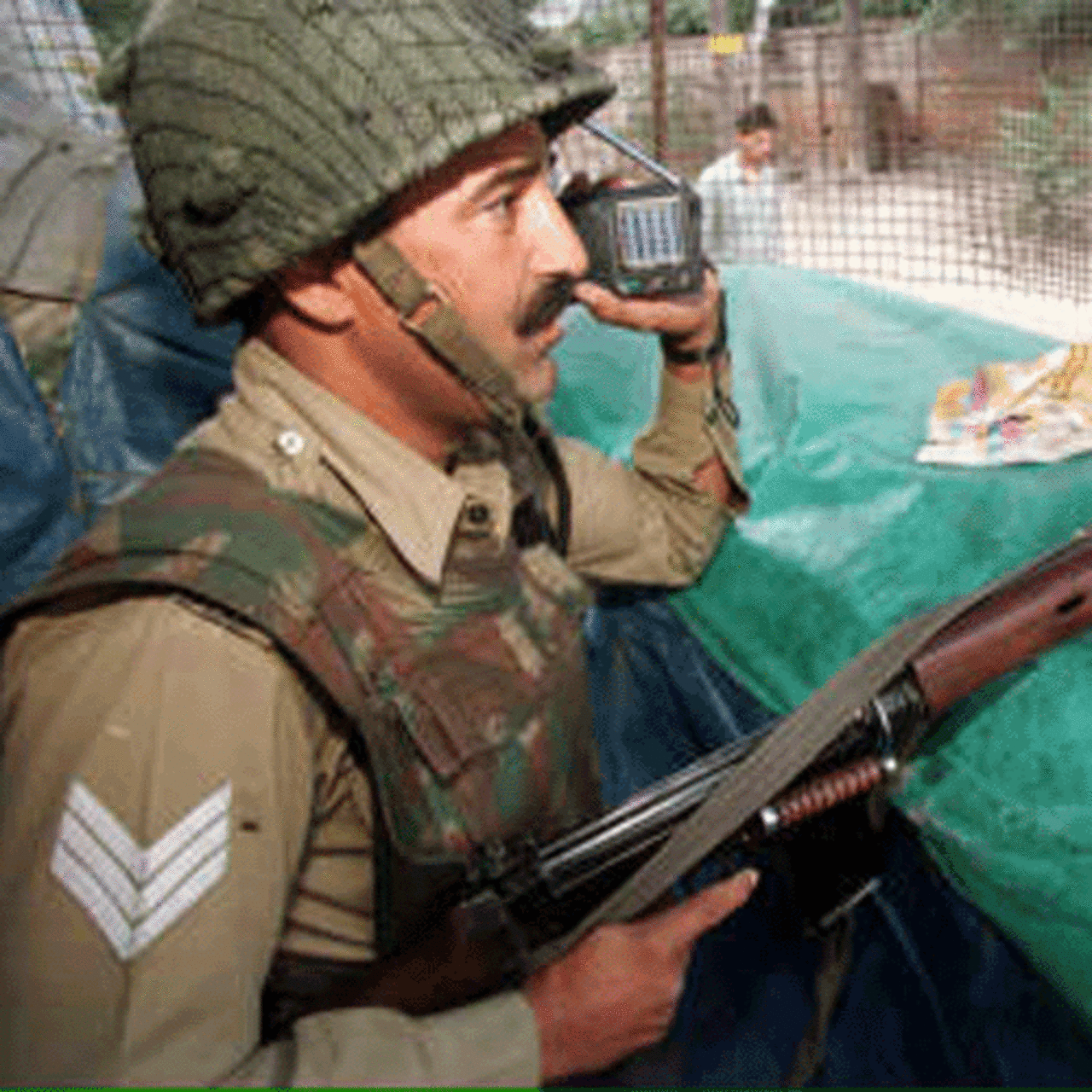 A Border Security Force officer listens to the cricket World Cup match pitting India against Pakistan on a transistor radio as he keeps watch from a bunker 08 June 1999 in Srinagar
