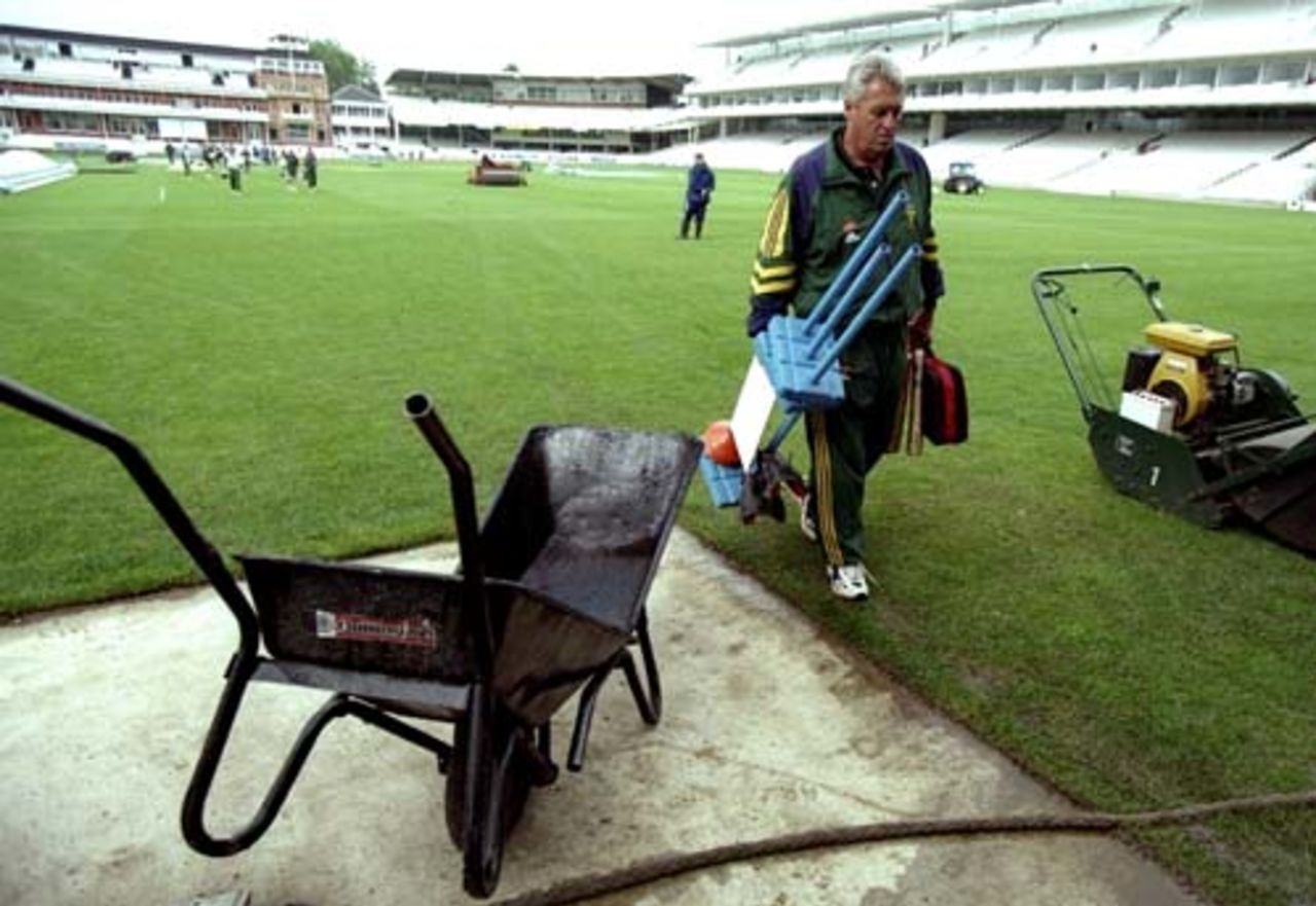 Bob Woolmer takes the equipment off the ground after a net session, June 1998