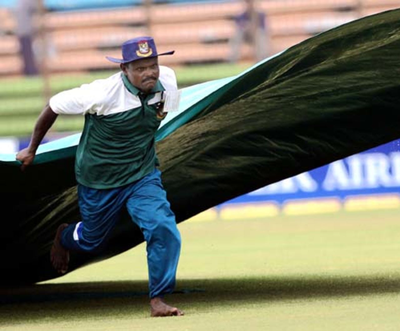 A groundsman pulls away the covers for play to resume, Bangladesh v India, 1st Test, Chittagong, 1st day