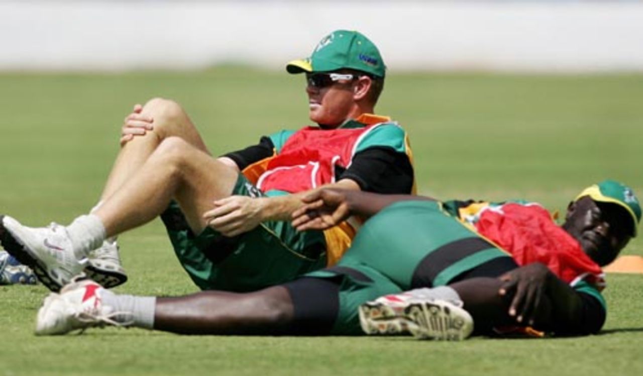 Shaun Pollock and Africa XI team-mate Thomas Odoyo stretch during a practice session at the Chinnaswamy Stadium, Bangalore, June 5, 2007