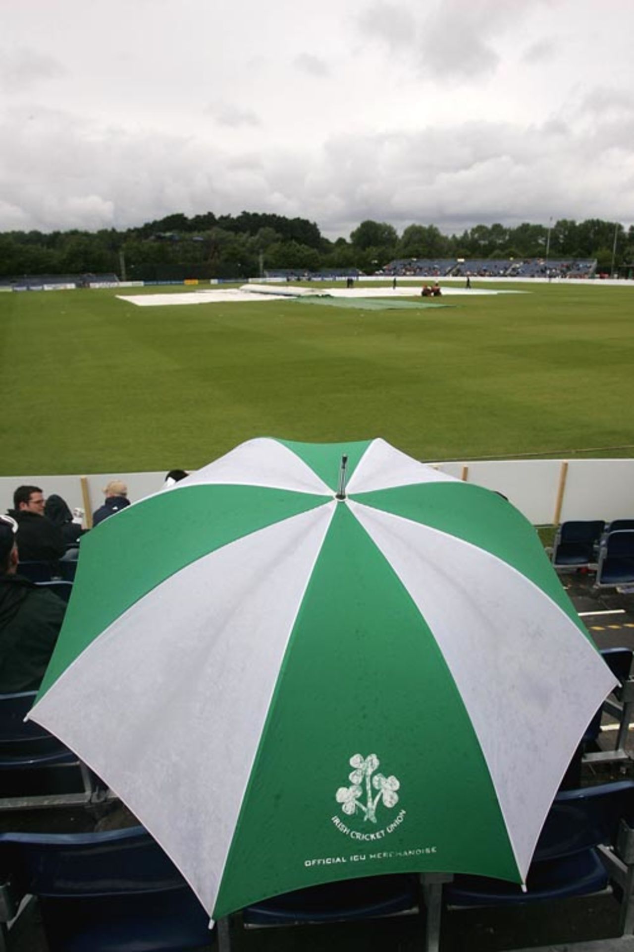 Spectators take shelter under an umbrella as rain delays the start at the Civil Service Cricket Club, Ireland v South Africa, One-off ODI, Belfast, June 24, 2007