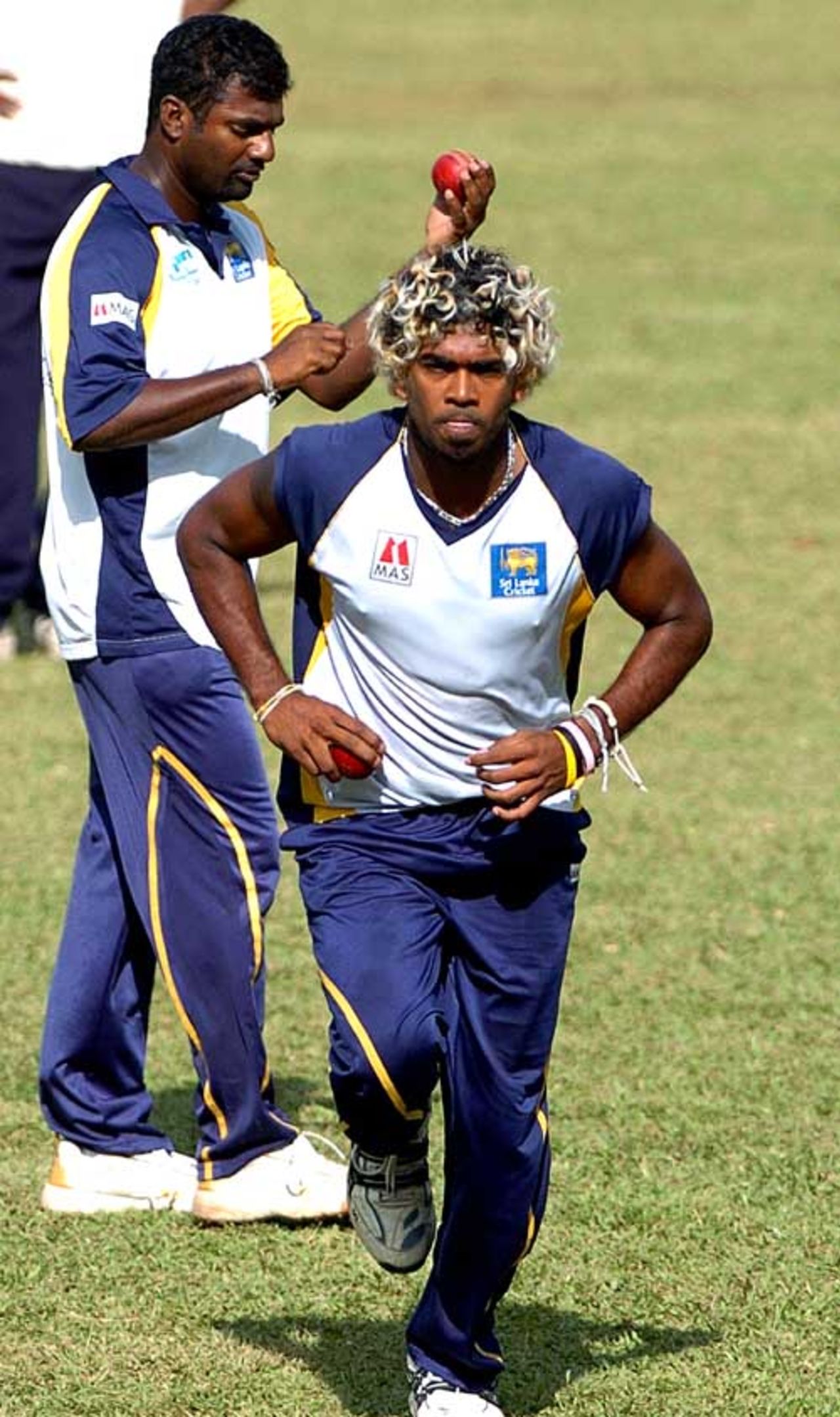 Lasith Malinga runs in to bowl while Muttiah Muralitharan waits his turn at a practice session, Kandy, July 9, 2007 