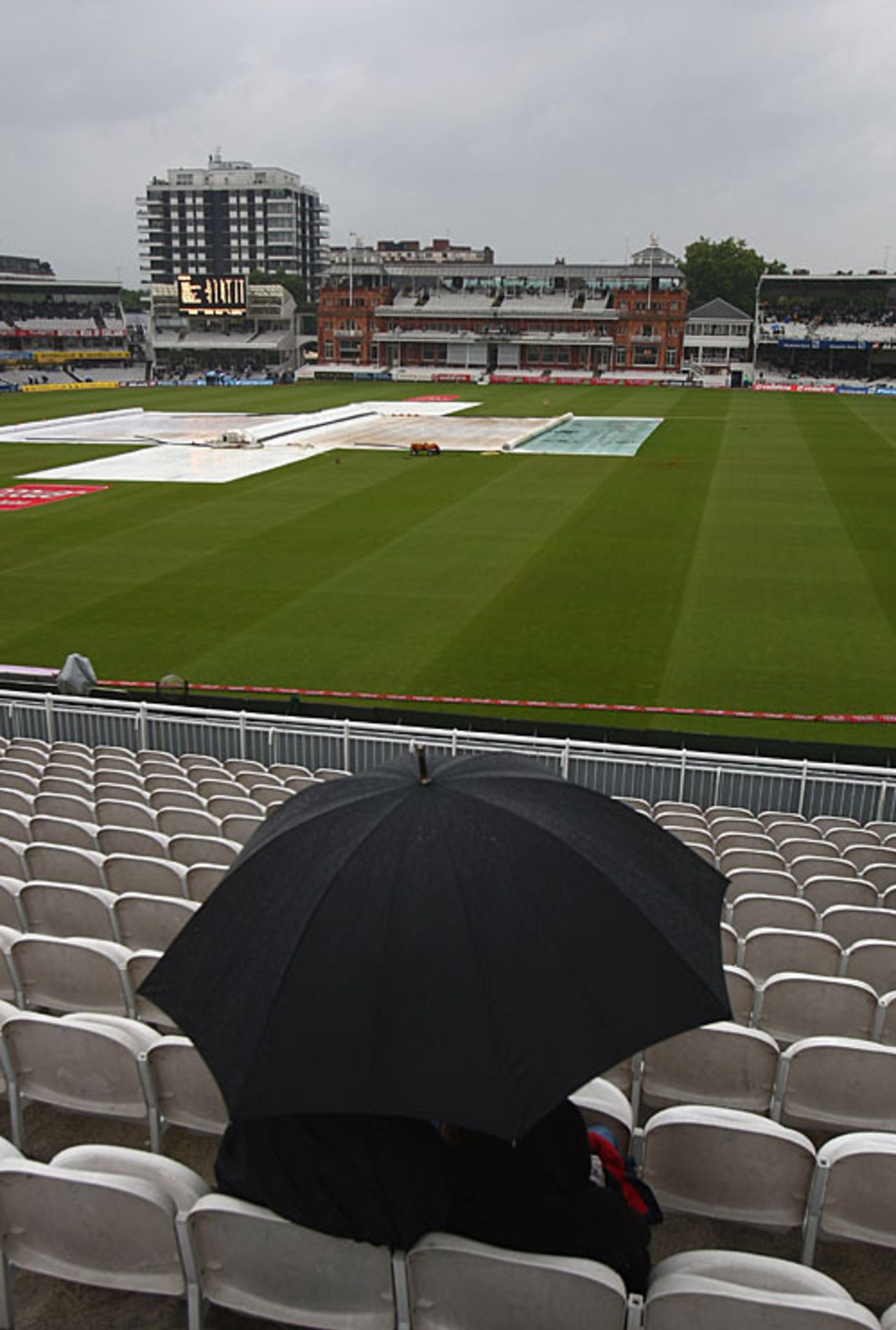 A lone fan shelters from the torrential rain under an umbrella at Lord's, England v India, 1st Test, Lord's, 2nd day, July 20, 2007