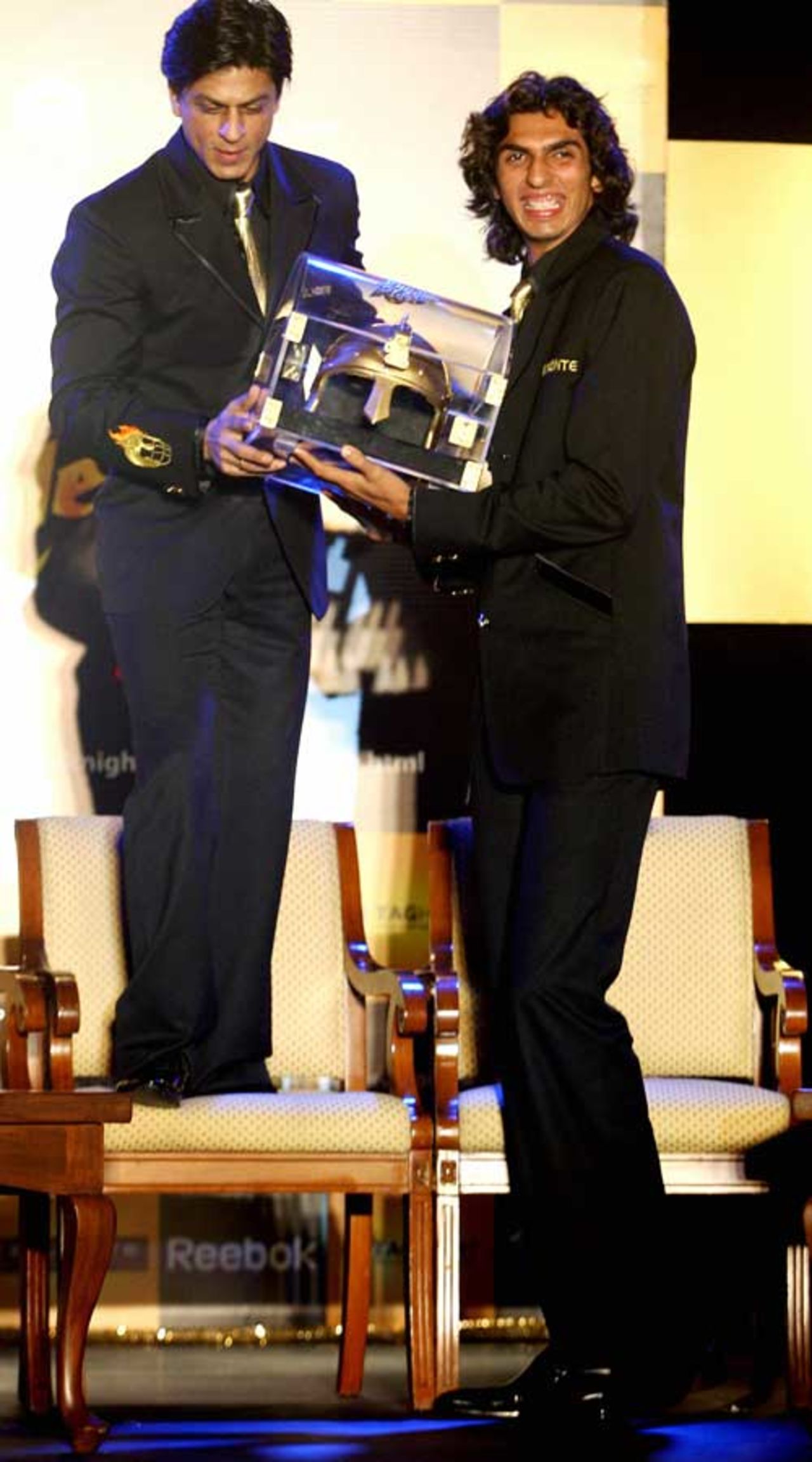 Indian actor and co-owner of the Kolkata Knight Riders cricket team, Shahrukh Khan (L) hands over a replica helmet to Pace bowler Ishant Sharma during a press meet in Mumbai on March 13, 2008