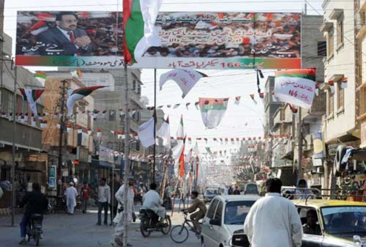 People walk along a street festooned with banners and posters of political parties in Karachi,  February 16, 2008