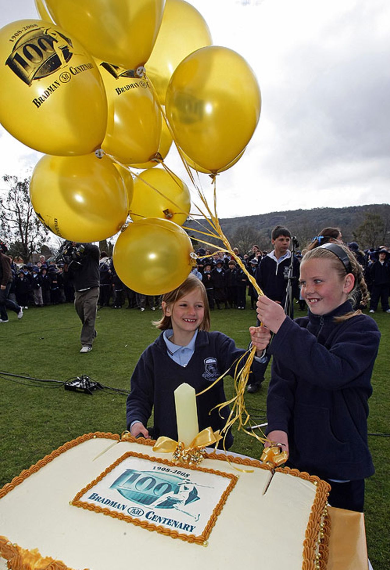 Schoolchildren prepare to cut a cake marking the centenary of Donald Bradman, Bowral, August 27, 2008