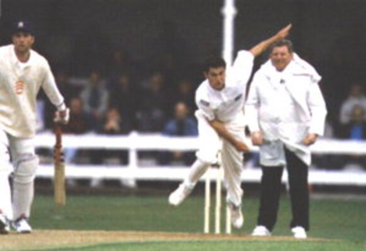 Darren Thomas bowling during the Championship match with Essex at Chelmsford in 1996, watched by batsman Ronnie Irani and umpire Graham Burgess.