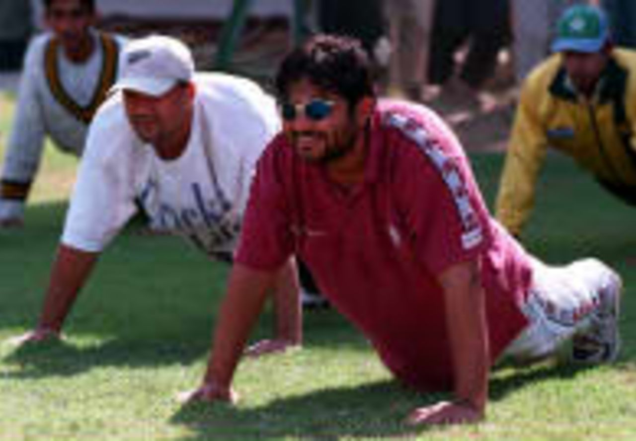 Pakistani bowler Mushtaq Ahmed (R) and wicketkeeper Moin Khan (L) take their exercise during a trail camp at the National Stadium to select the players for the upcoming Indian tour in Karachi 12 January 1998.