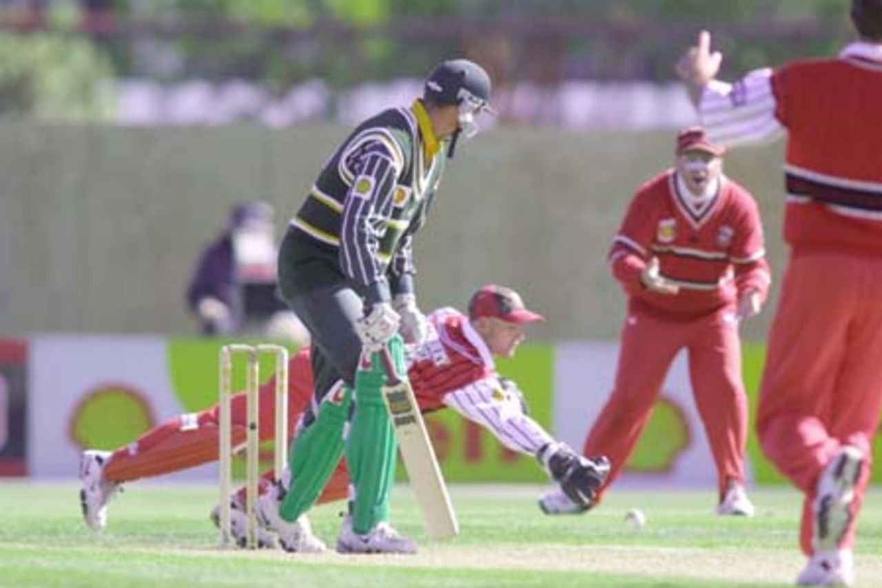 Canterbury wicket-keeper Gareth Hopkins unsuccessfully dives to have a second attempt at a catching chance which spilled from his grasp, coming off the edge of number 11 batsman Brent Hefford during his innings of 16. The bowler is Nathan Astle, with Brad Doody looking on in the background. 2nd Shell Cup Final: Canterbury v Central Districts at Jade Stadium, Christchurch, 27 January 2001.