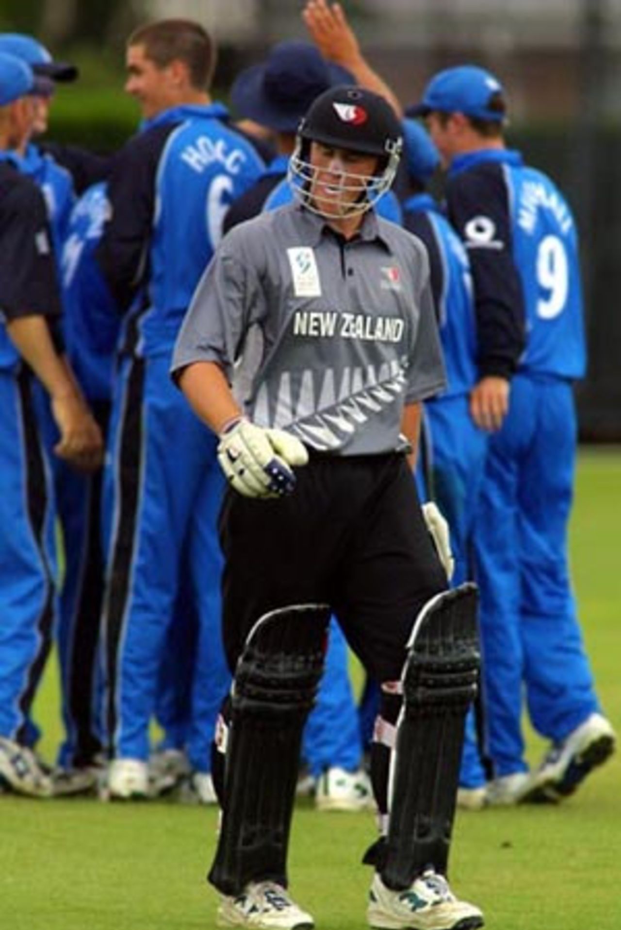 New Zealand Under-19 batsman Jordan Sheed walks from the field after being dismissed as England Under-19 players celebrate in the background. Sheed was caught by wicket-keeper Stephen Pope from the bowling of Kyle Hogg for one. ICC Under-19 World Cup Super League Group 2: England Under-19s v New Zealand Under-19s at Lincoln No. 3, Lincoln, 28 January 2002.