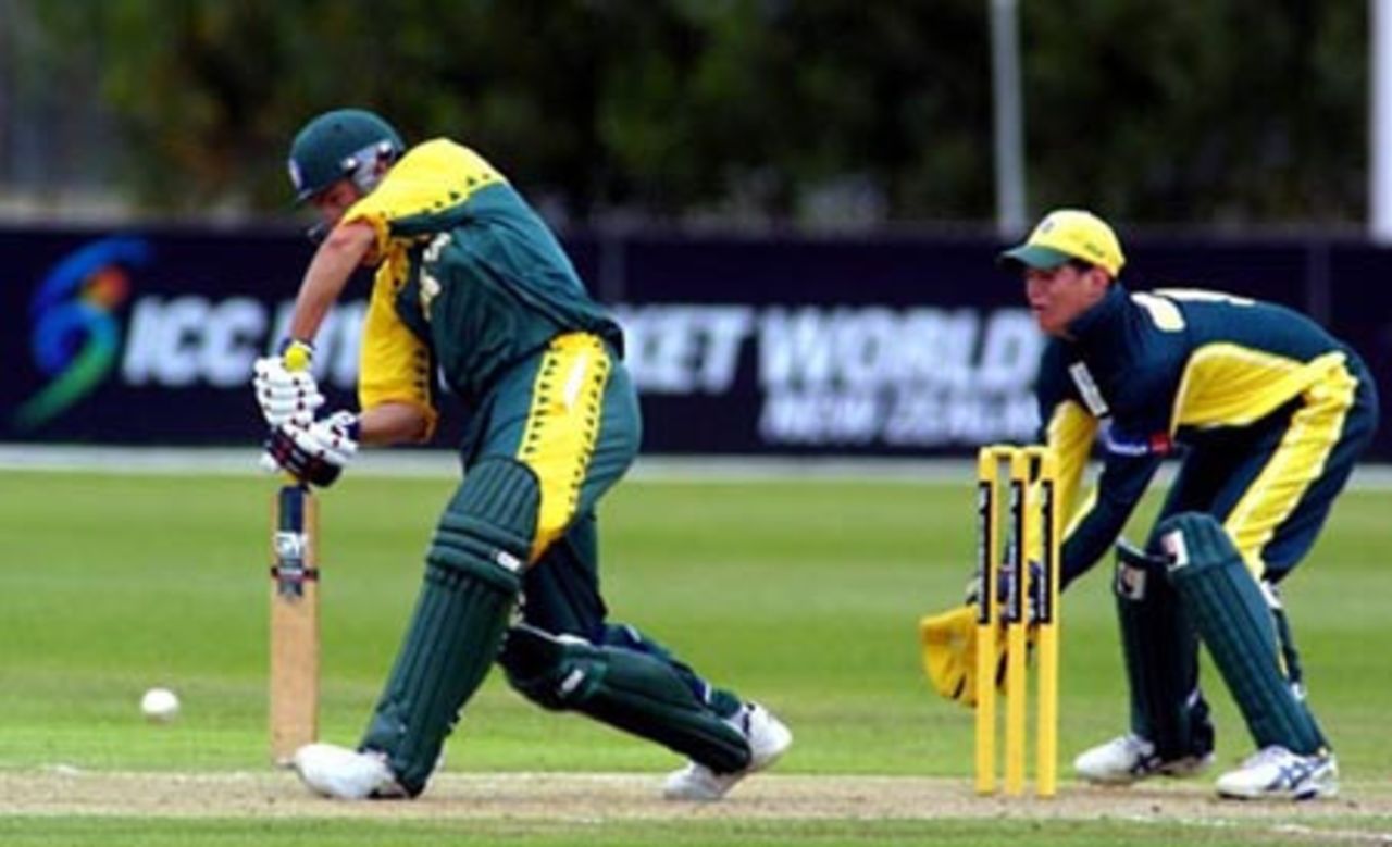 South Africa Under-19 batsman Stephen Cook stretches forward to defend a delivery during his innings of 48. Australia Under-19 wicket-keeper Adam Crosthwaite looks on. ICC Under-19 World Cup Super League Group 2: Australia Under-19s v South Africa Under-19s at Bert Sutcliffe Oval, Lincoln, 28 January 2002.