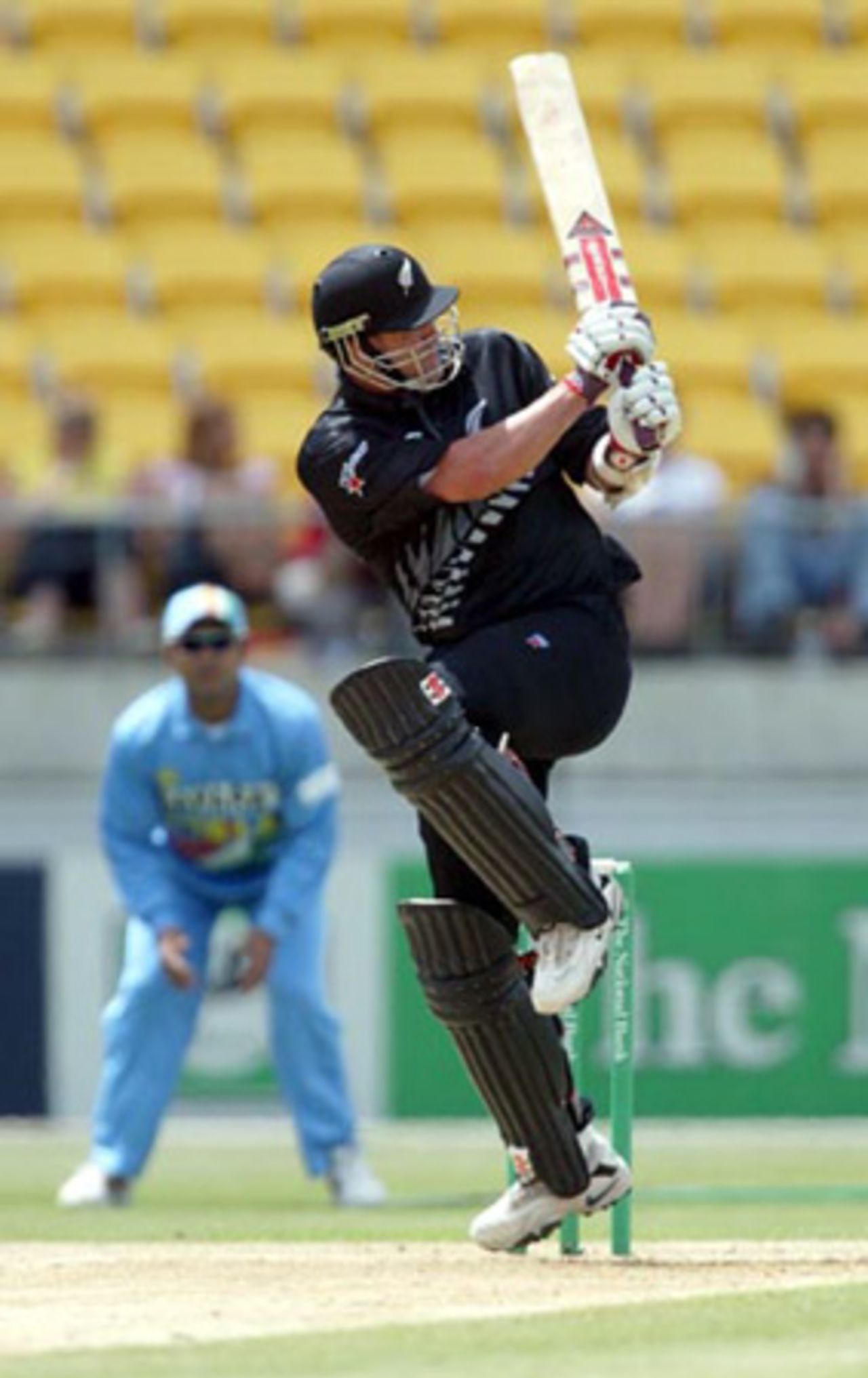 New Zealand batsman Chris Cairns pulls a delivery through square leg during his innings of 25. Indian slip fielder Virender Sehwag look on in the background. 5th ODI: New Zealand v India at Westpac Stadium, Wellington, 8 January 2003.