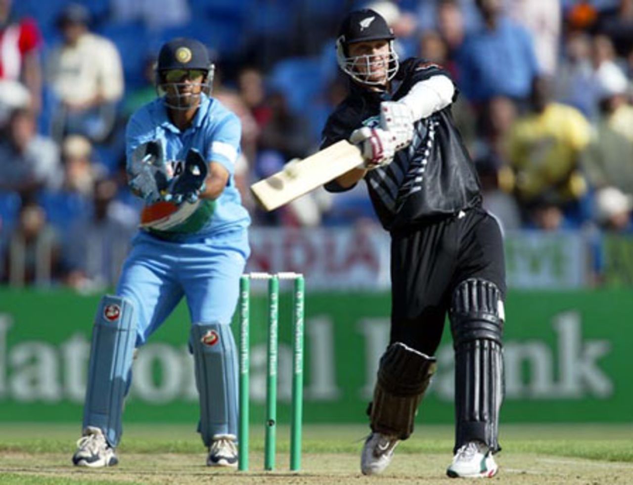 New Zealand batsman Shane Bond hits a delivery from Indian bowler Sourav Ganguly for six during his innings of 31 not out as wicket-keeper Rahul Dravid looks on. 6th ODI: New Zealand v India at Eden Park, Auckland, 11 January 2003.
