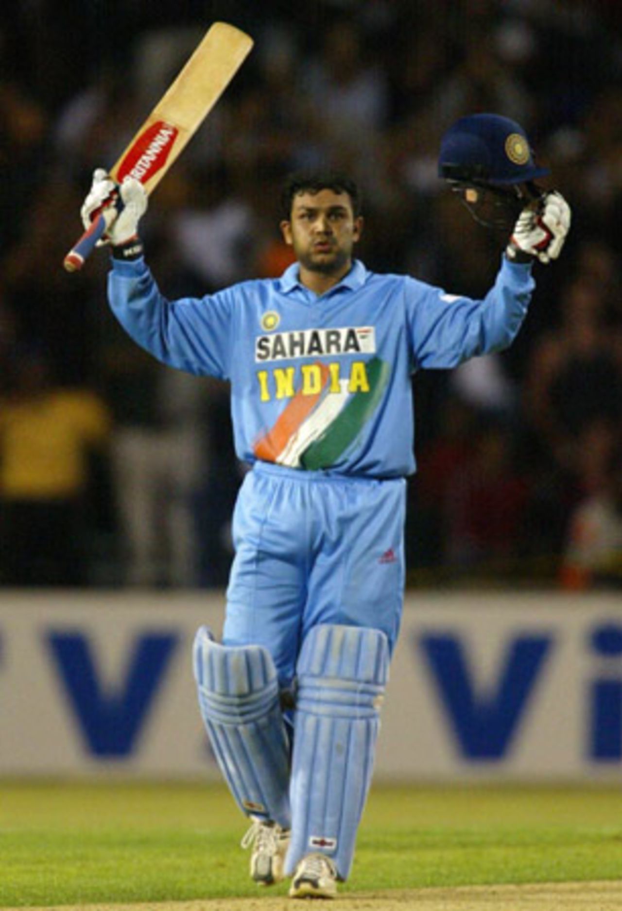 Indian batsman Virender Sehwag raises his bat and helmet to celebrate reaching his century. Sehwag went on to score 112. 6th ODI: New Zealand v India at Eden Park, Auckland, 11 January 2003.