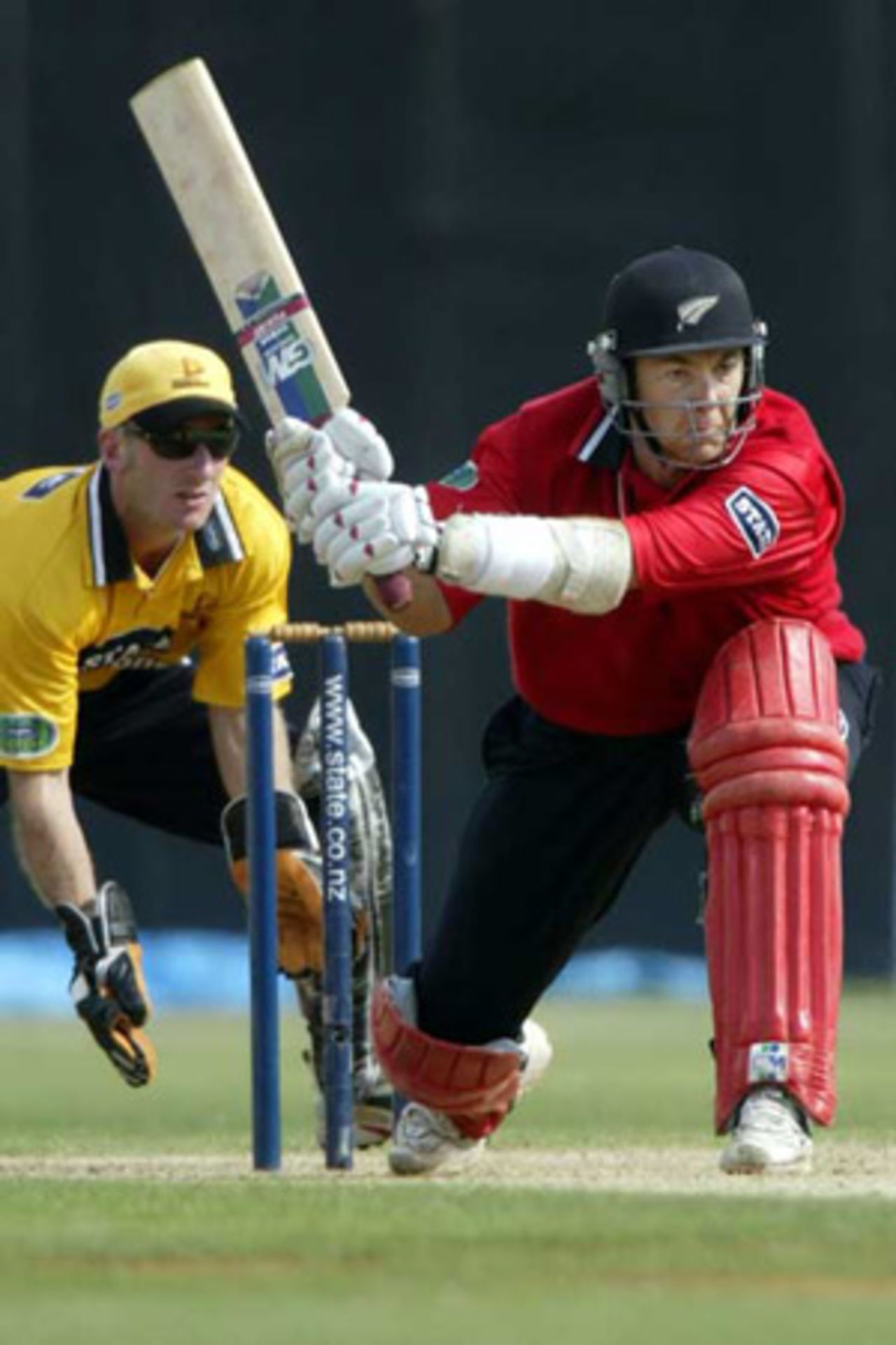 Canterbury batsman Craig McMillan sweeps a delivery during his innings of 122 not out as Wellington wicket-keeper Chris Nevin looks on. State Shield: Wellington v Canterbury at Basin Reserve, Wellington, 19 January 2003.