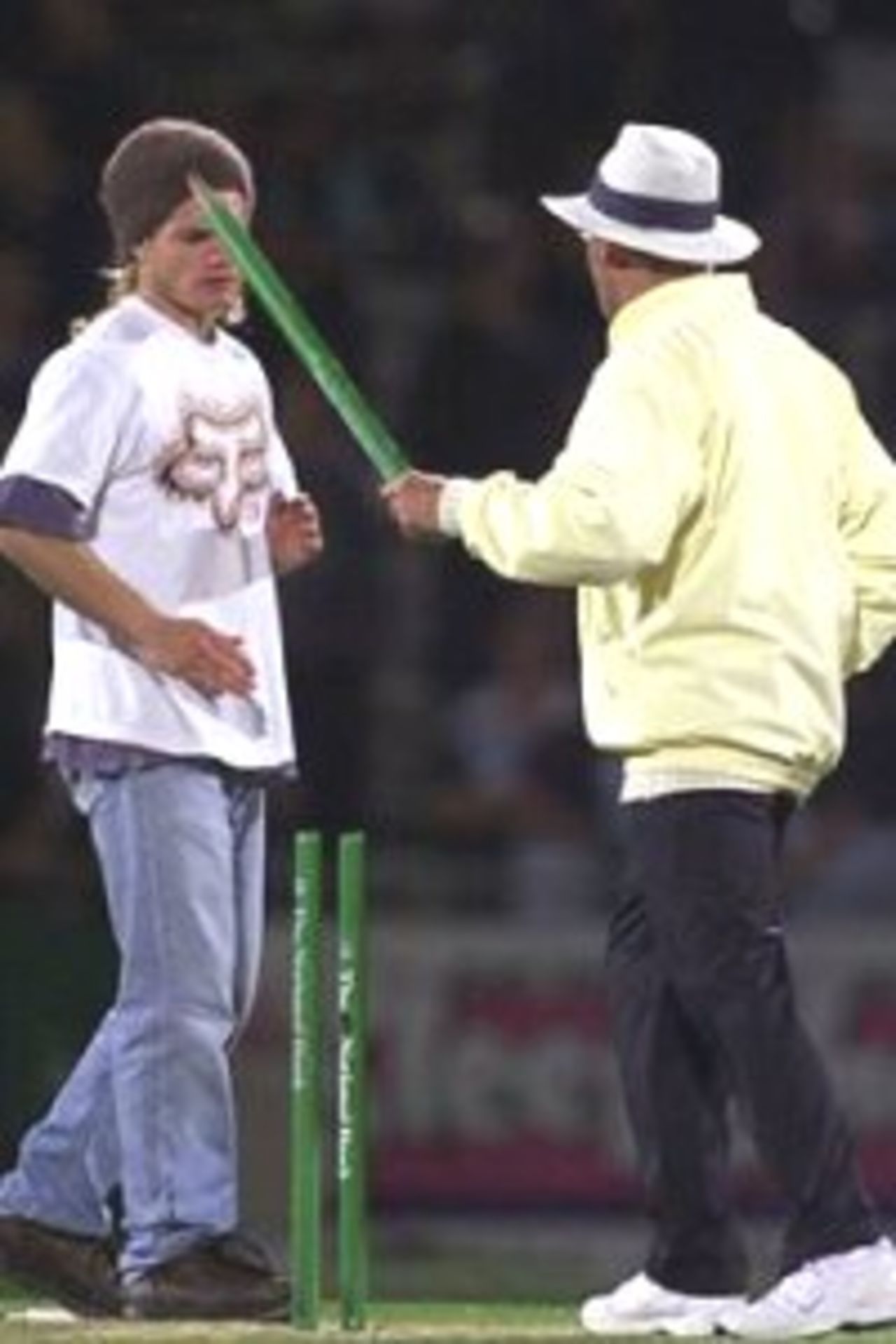 23 Feb 2000: Umpire Steve Dunne (right) threatens a fan trying to souvenir the wickets, with a stump after the third one day international between New Zealand and Australia at Carisbrook, Dunedin, New Zealand.