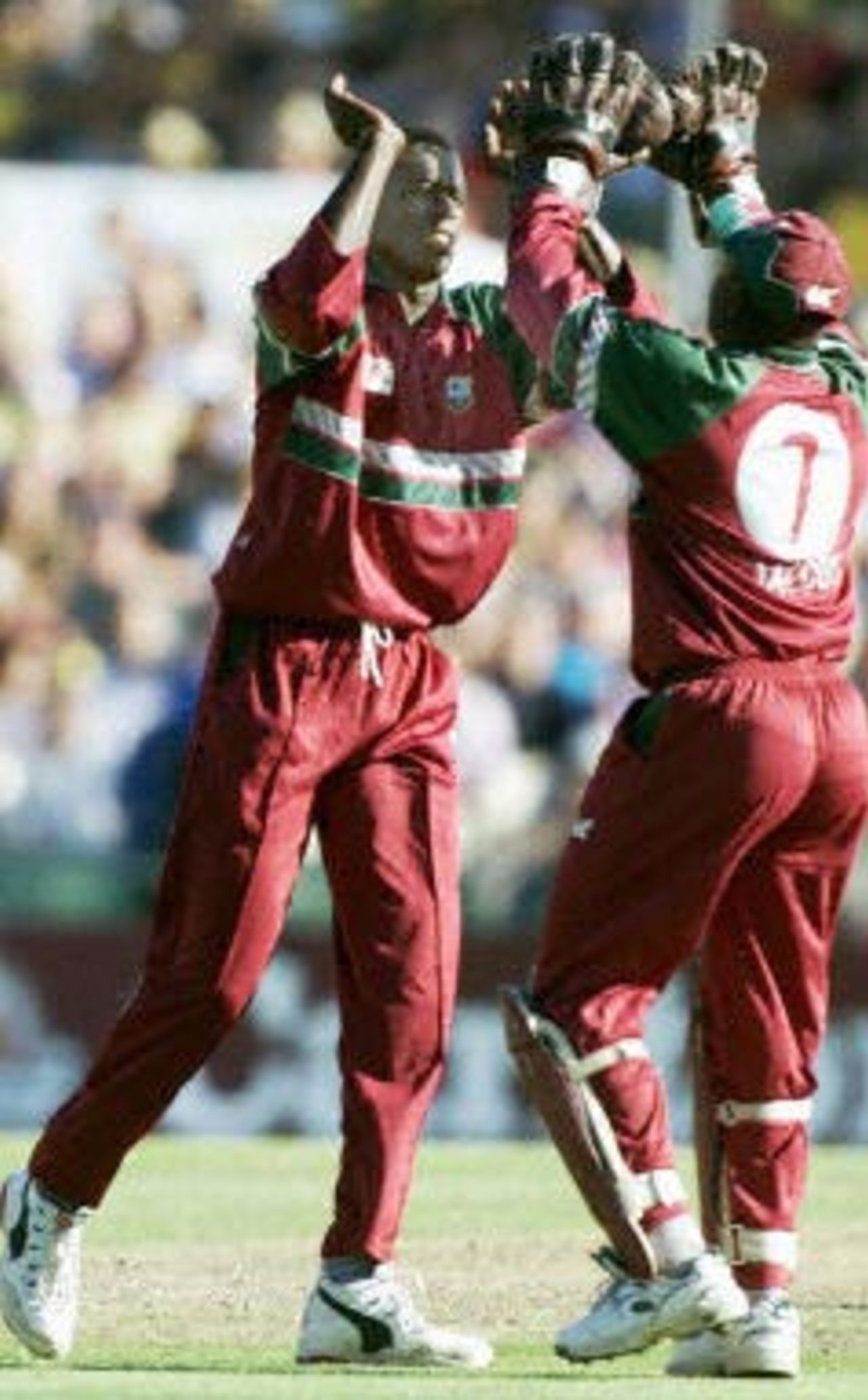West Indies fast bowler Cameron Cuffy (L) celebrates taking the wicket of Australia's Shane Warne with West Indies wicket-keeper Ridley Jacobs (R) during the first cricket final between Australia and the West Indies in Sydney 07 February 2001. Warne was caught by Jacobs for 7 runs. Australia have set a target 254 for the West Indies to chase at the end of 50 overs.