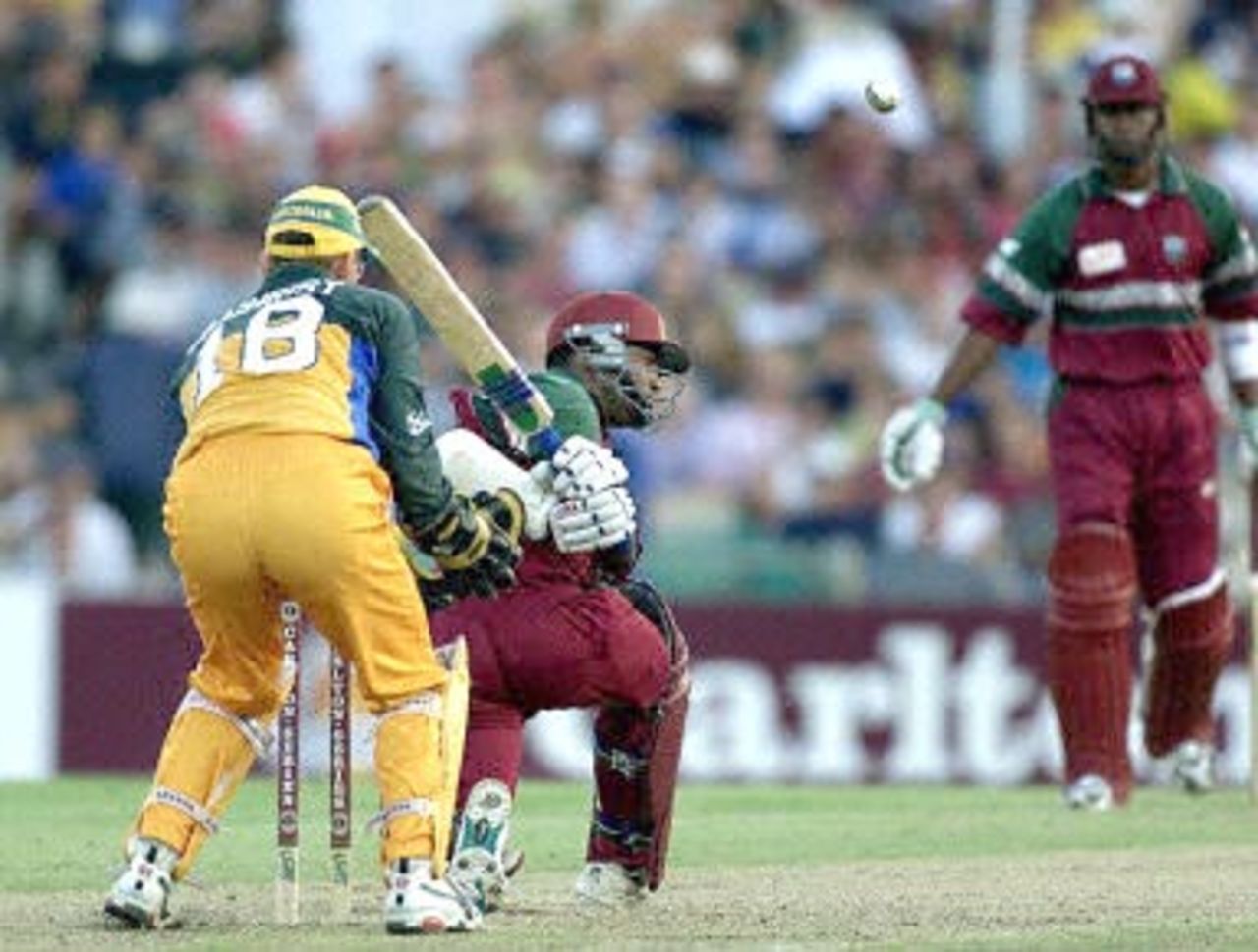 West Indies star batsman Brian Lara (C) sweeps at a ball from Australia's Shane Warne as Australian wicket-keeper Adam Gilchrist (L) and batting partner Marlon Samuels (R) look on at the first Final of the Tri Nations series in Sydney 07 February 2001. Lara who hit seven boundaries from 38 balls was caught, Gilchrist bowled Fleming for 35.