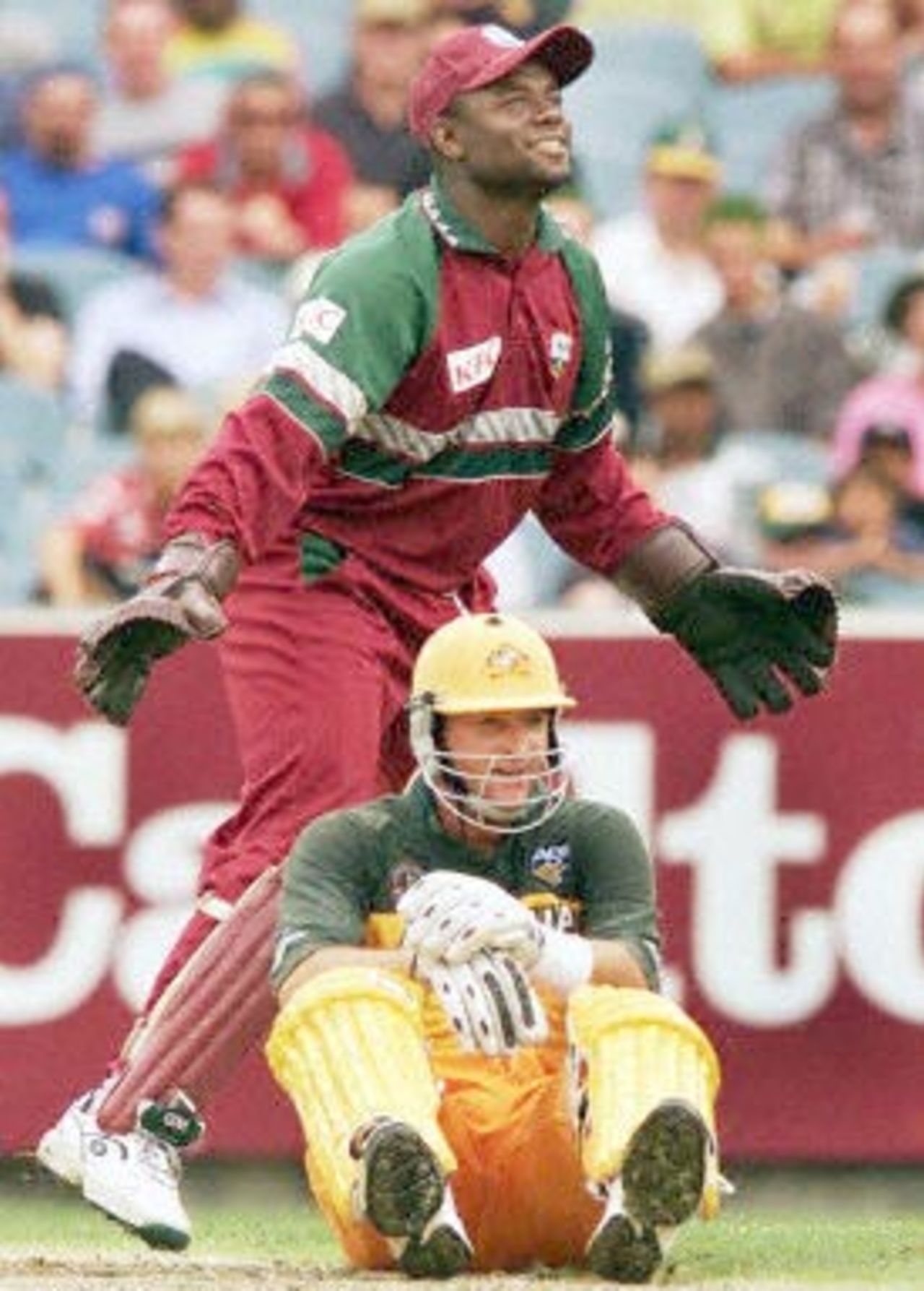 West Indian wicketkeeper Ridley Jacobs (top) smiles as Australian batsman Mark Waugh sits on the ground after slipping over during the second one-day final against the West Indies at the MCG in Melbourne 09 February 2001. Australia amassed the huge total of 338-6 with Mark Waugh topscoring with 173.