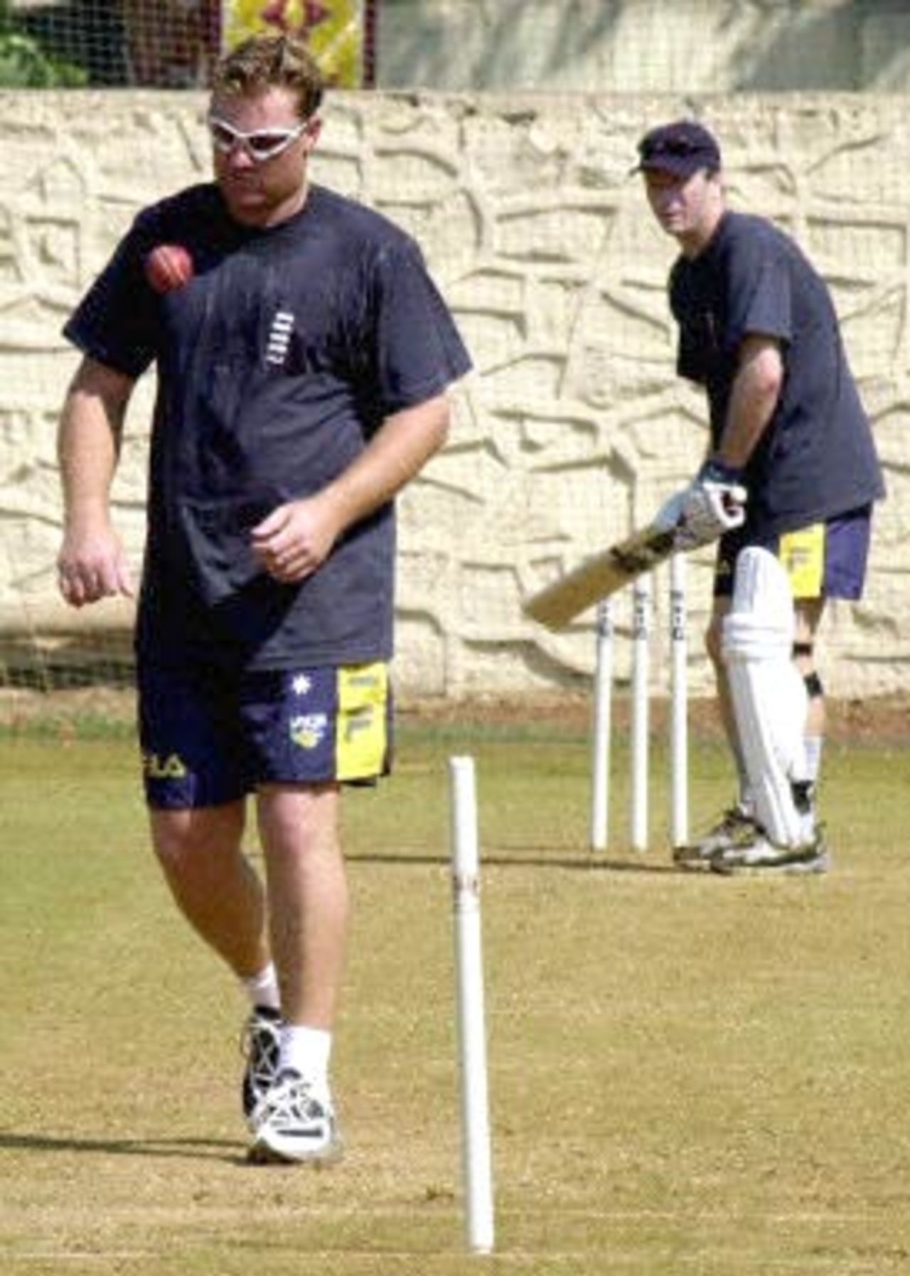 Australian leg spinner Shane Warne tosses the ball before his next delivery to team-mate Steve Waugh (R), 15 February 2001 in Mumbai,during a practice session. Warne will relish his return meeting with his greatest tormentor Sachin Tendulkar who had wrecked Warne's bowling in a Test series in India three years ago.
