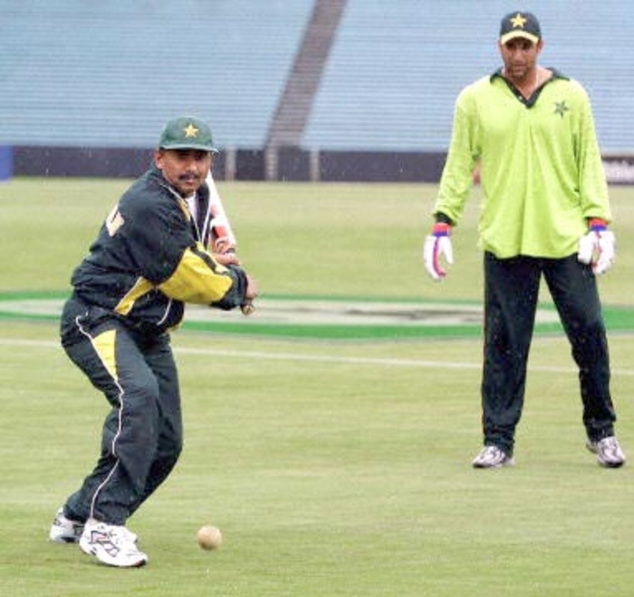 Pakistani coach Javid Miandad (L) prepares to play at a ball while Wasim Akram plays wicketkeeper during a light training session in rainy conditions for the Pakistan cricket team at Eden Park in Auckland, 16 February 2001. Pakistan will play New Zealand's Black Caps in the first of five one-day internationals starting 17 February.
