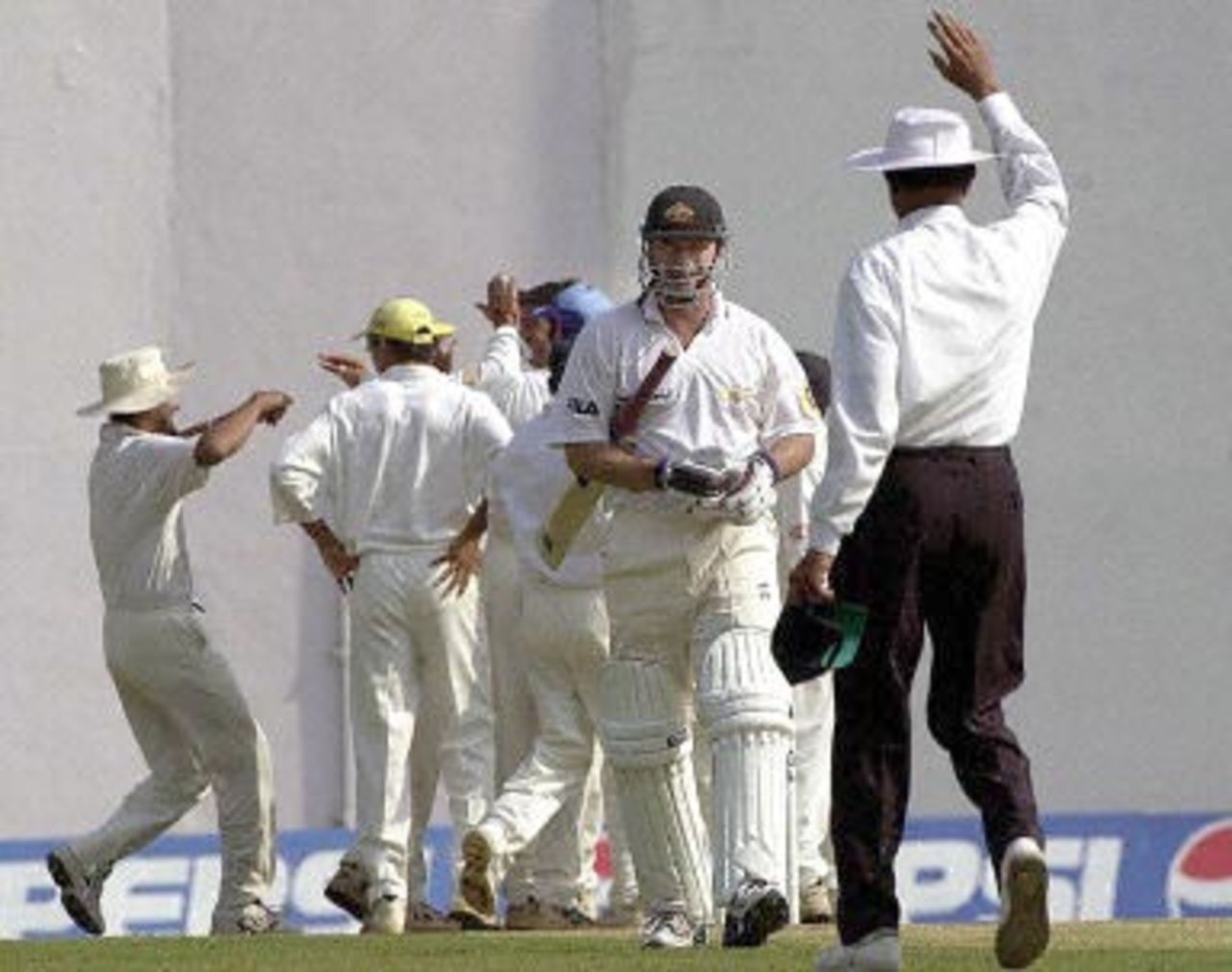 Indian players celebrate (background) the dismissal of Australian skipper Steve Waugh (w/bat) as he returns to the pavillion on the first day of the first three-day test match in Nagpur, 17 February 2001. Australia were 116 for 4 after two hours of play.