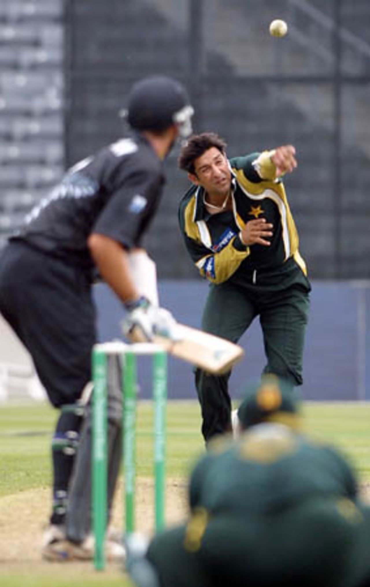 Pakistan fast medium bowler Wasim Akram delivers a ball to New Zealand batsman Craig McMillan during his spell of 0-62 from 10 overs while wicket-keeper Moin Khan looks on in the foreground. 4th One-Day International: New Zealand v Pakistan at Jade Stadium, Christchurch, 25 February 2001.