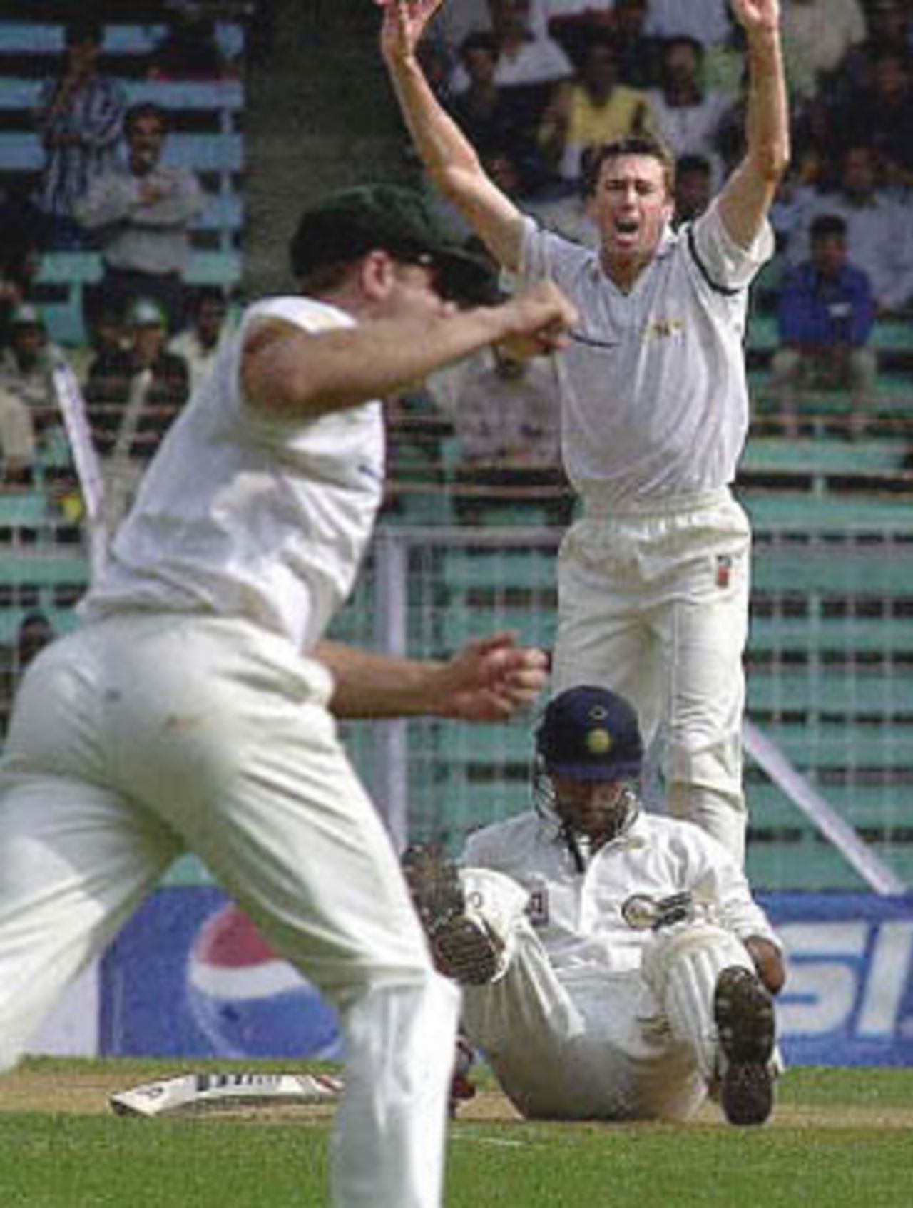 Australian pace bowler Glenn McGrath (R-top) celebrates after claiming the wicket of fallen Indian batsman Sadagopan Ramesh (R-bottom) on the opening day of the first Test match between India and Australia at Wankhade stadium in Bombay, 27 February 2001. Australia turned the screws on India at the start of the Test, reducing the hosts to 62 for 4 by lunch. Player at L is unidentified.