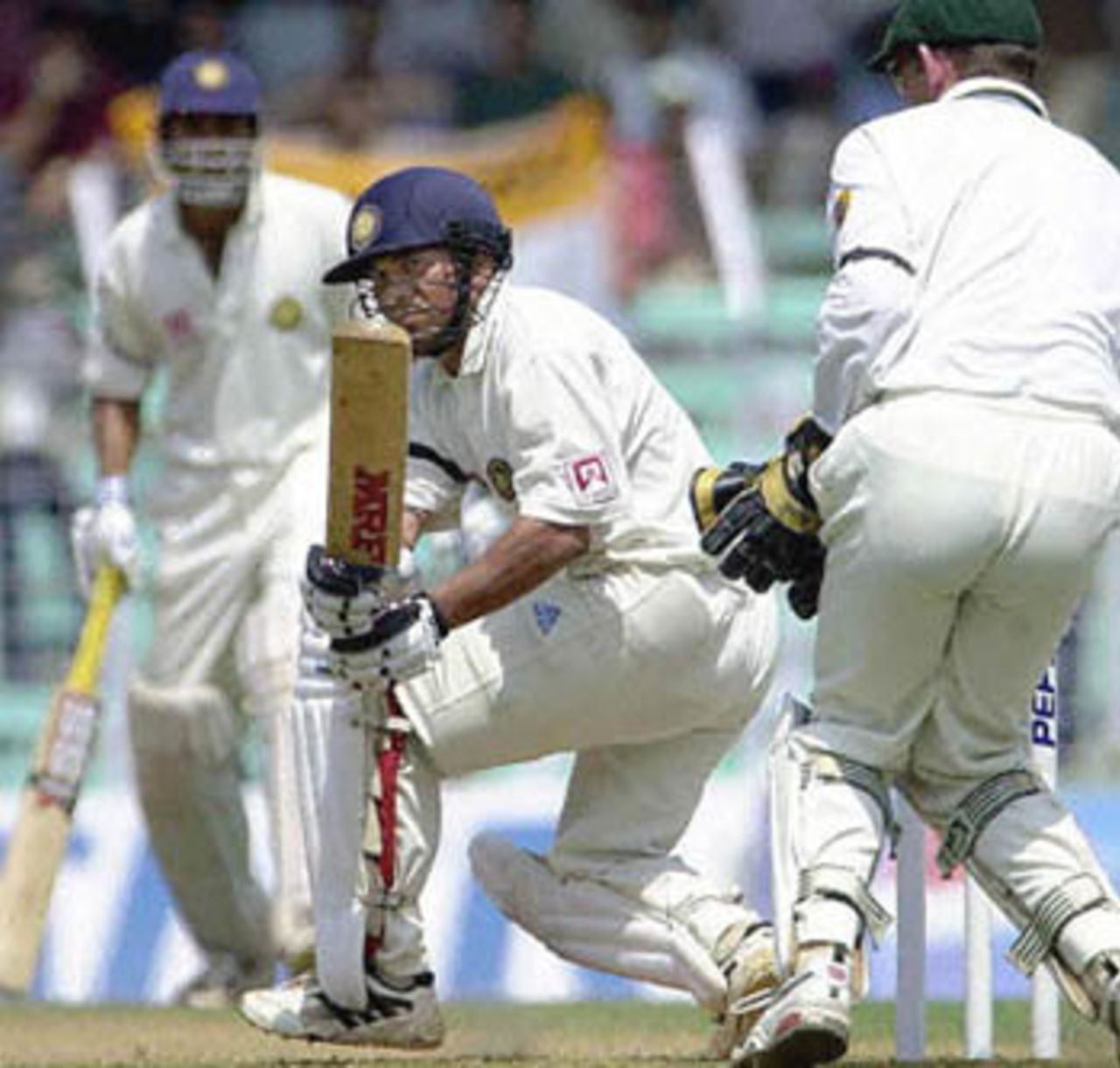 Indian batsman Sachin Tendulkar (C) sweeps a delivery from Austrlian spinner Shane Warne (not pictured) as teammate Venkat Sai Laxman (L) and Australian wicketkeeper Adam Gilchrist (R) look on during the opening day of the first Test match between Indian and Australia at Wankhade stadium in Bombay, 27 February 2001. Tendulkar scored a valuable 76 runs as the India were struggling at 140 for 7 wickets.