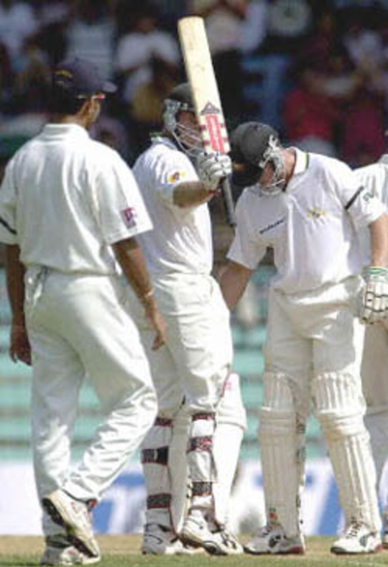 Australian batsman Matthew Hayden(C), flanked by Indian player Rahul Dravid (L) and Australin team-mate Adam Gilchrist (R), raises his bat to acknowledge the cheering crowd after completing his half century on the second day of the first test match between India and Australia at Wankhade stadium in Bombay 28 February 2001. Hayden scored an unbeaten 81 by lunch to steady Australia's staggering first innings to 170 for 5 in reply to India's 176 runs.