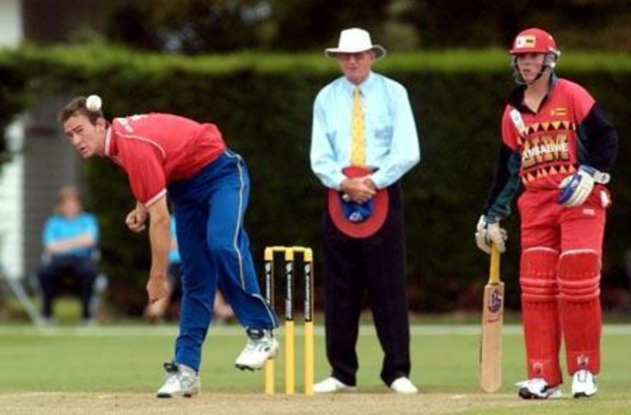 Namibia Under-19 bowler Hendrik Geldenhuys delivers a ball during his spell of 1-24 from 10 overs. Umpire Tony Cooper from Fiji and Zimbabwe Under-19 batsman Brendon Taylor look on. 1st ICC Under-19 World Cup Plate Championship Semi Final: Namibia Under-19s v Zimbabwe Under-19s at Lincoln No. 3, Lincoln, 4 February 2002.