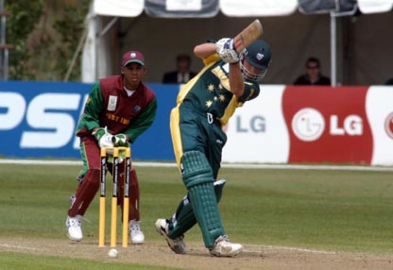 Australia Under-19 batsman Craig Simmons drives down the ground during his innings of 84. West Indies Under-19 wicket-keeper Lendl Simmons looks on. 2nd ICC Under-19 World Cup Super League Semi Final: Australia Under-19s v West Indies Under-19s at Bert Sutcliffe Oval, Lincoln, 6-7 February 2002 (7 February 2002).
