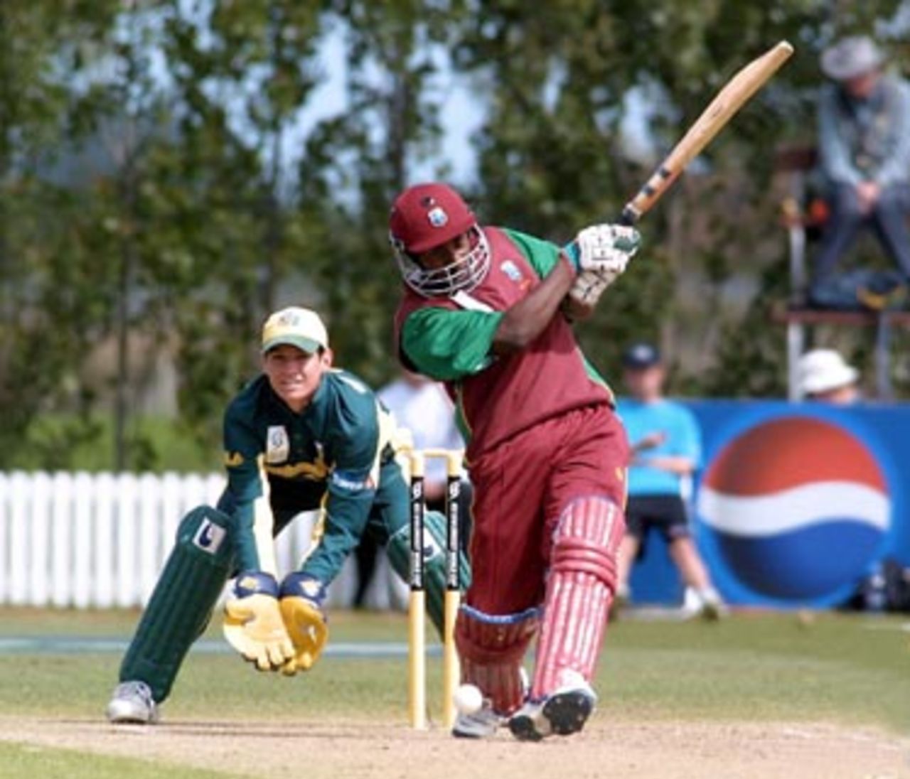 West Indies Under-19 batsman Tonito Willett hits a delivery down the ground during his innings of 83. Australia Under-19 wicket-keeper Adam Crosthwaite looks on. 2nd ICC Under-19 World Cup Super League Semi Final: Australia Under-19s v West Indies Under-19s at Bert Sutcliffe Oval, Lincoln, 6-7 February 2002 (7 February 2002).