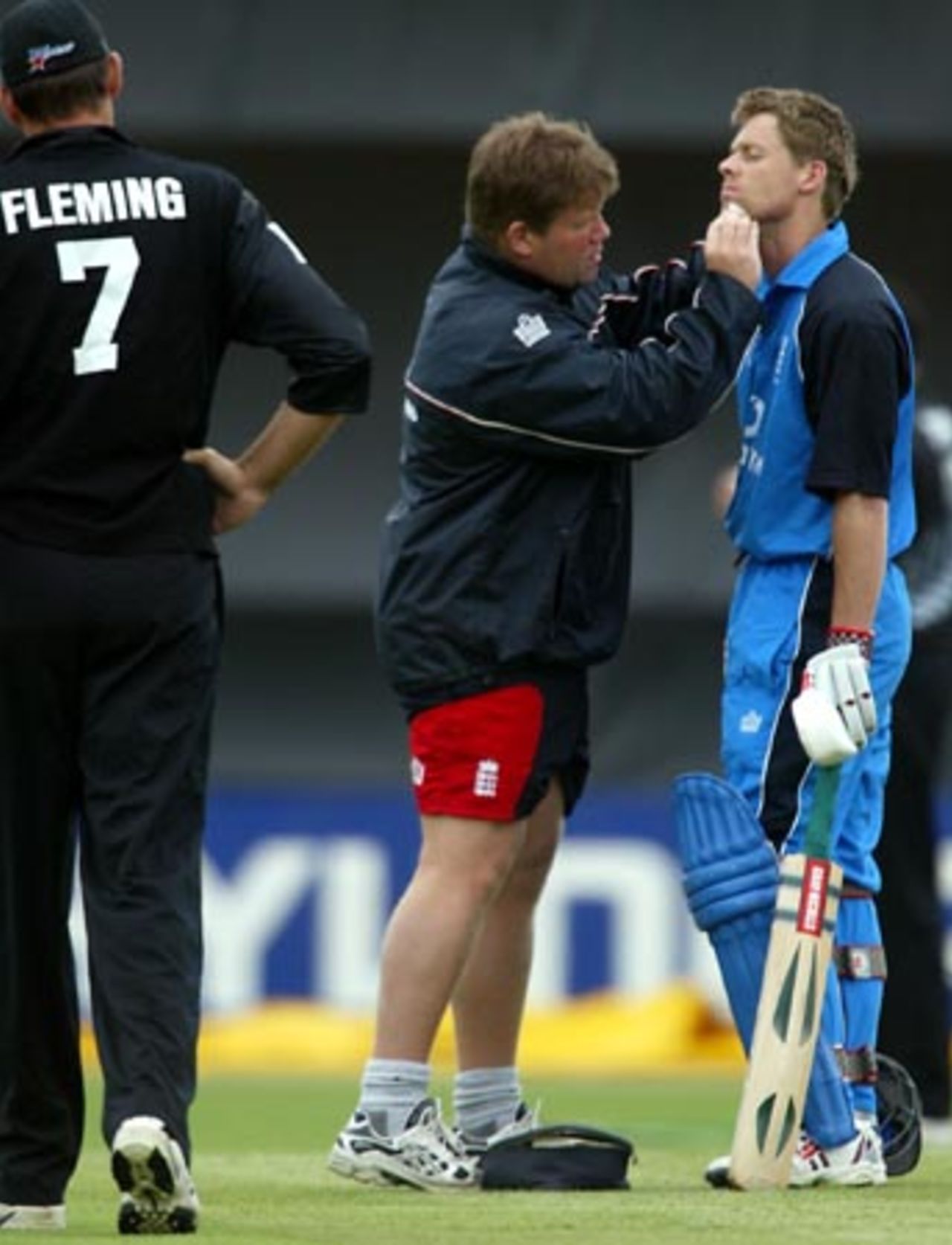England batsman Nick Knight receives medical attention from physiotherapist Dean Conway for a cut on his chin after top-edging a bouncer from the bowling of Ian Butler during his innings of 80. New Zealand fielder Stephen Fleming looks on. 3rd ODI: New Zealand v England at McLean Park, Napier, 20 February 2002.