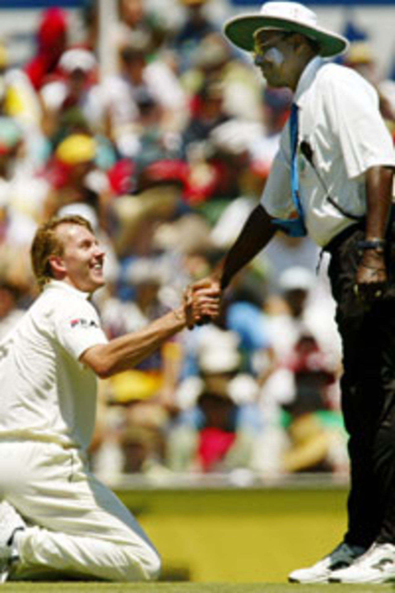 Australian paceman Brett Lee (L) is helped to his feet by umpire Steve Bucknor after being felled by a wayward throw on the second day of the fourth Test Match against India in Sydney, 03 January 2004. At tea, India was 495-3.