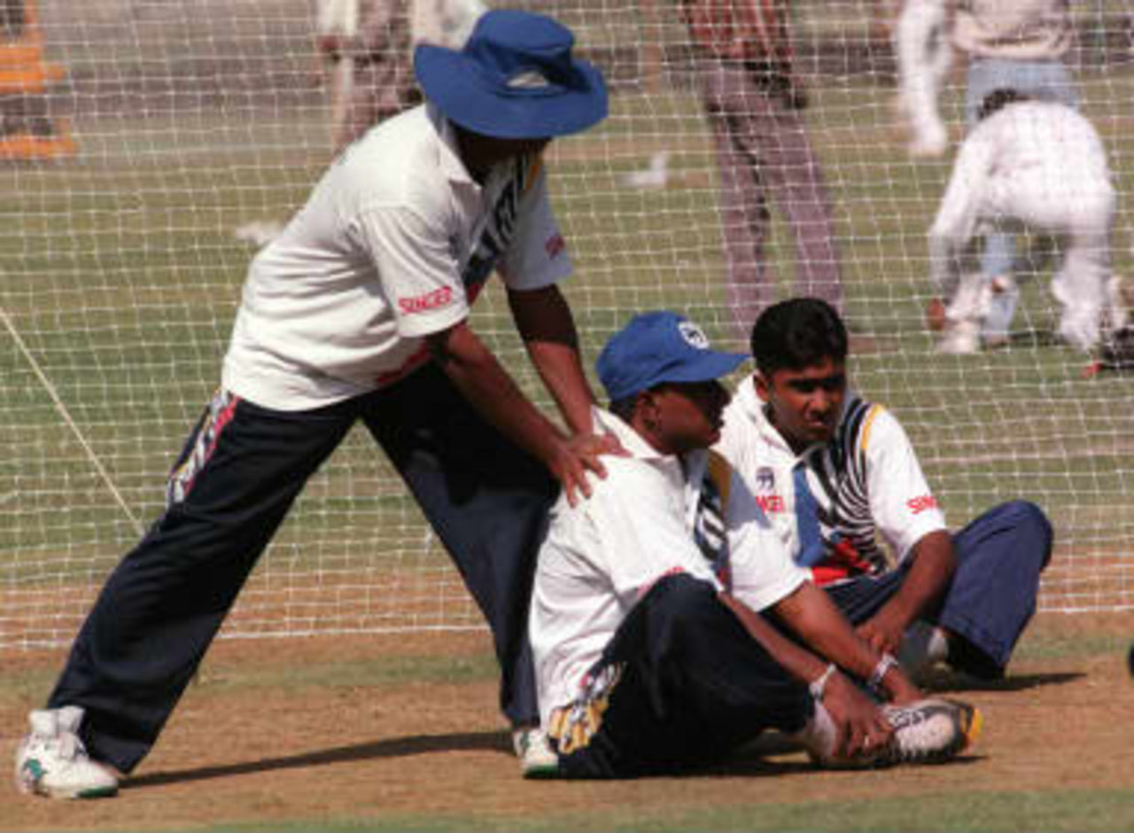 Sri Lankan trainer helps star batsman Arvind a D'Silva loosen his shoulder muscles while team-mate Mehala Jayawardhne watches, at net practice 29 March 1999, at the Nehru stadium in Pune.