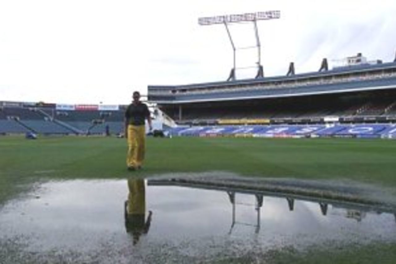14 Mar 2000: A ground staff worker walks across a huge puddle of water, as play is abandoned due to bad weather on day four of the first test match between New Zealand and Australia, Eden Park, Auckland, New Zealand.