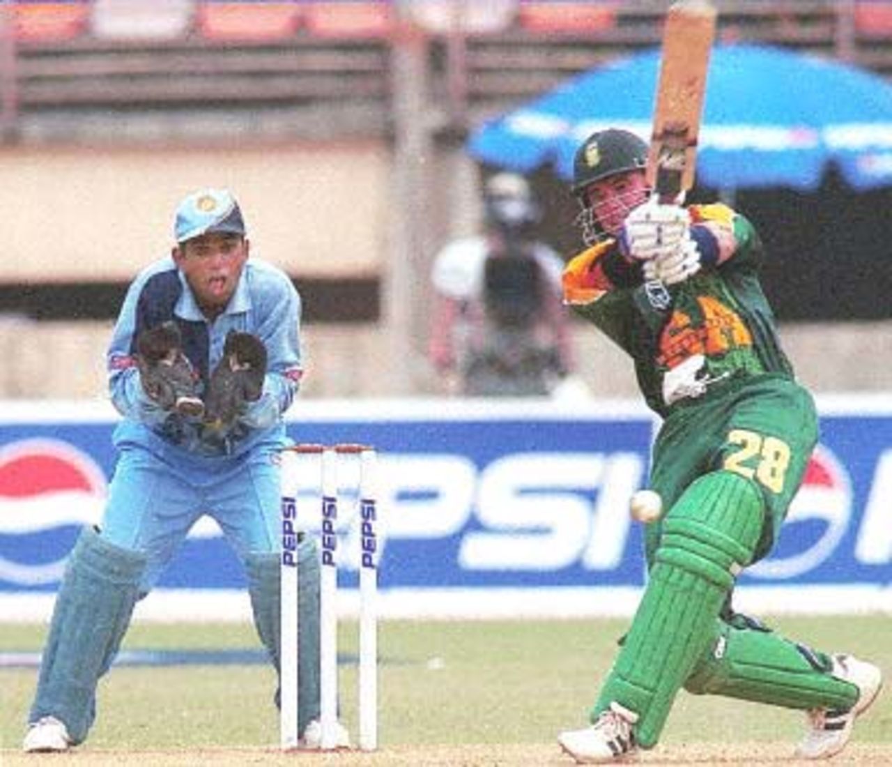 South African batsman Herschelle Gibbs (R) cracks the ball to the boundary on his way to making 111 useful runs ,as Indian wicket keeper Samir Dighe looks on during the first one-day international cricket match between India and South Africa in Cochin 09 March 2000. Despite Gibbs' sparkling century, India went on to beat South Africa by three wickets