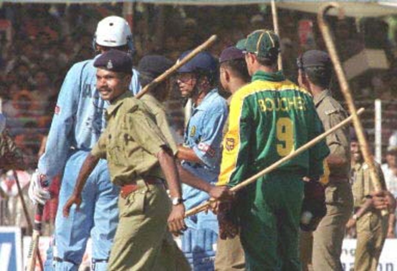 Riot police protect Indian cricketer Sachin Tendulkar (C) from pitch-invading fans 17 March 2000, after he scored a century against South Africa at the IPCL grounds in Baroda, India. India won the fourth of five matches in the series to take an unbeatable 3-1 lead