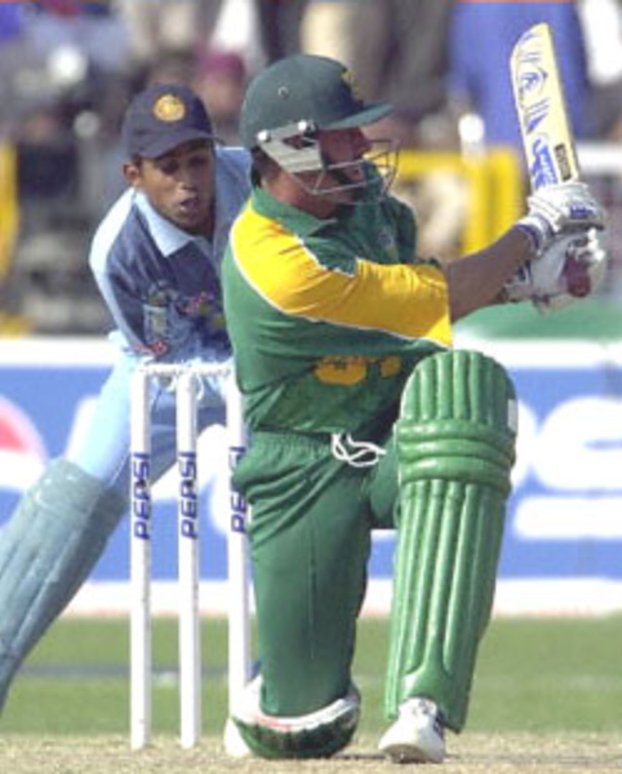 South African captain Hansie Conjie (R) sweeps the ball to the fence on his way to scoring a quick 66 runs off 77 balls, fetching him the ' man of the match during the third one-day international cricket match between South Africa and India played at Faridabad, 15 March 2000, as Indian wicket keeper Sameer Dighe (R) looks on. South Africa went on to beat  India by two wickets as the five match series stands at 2-1 in favour of India